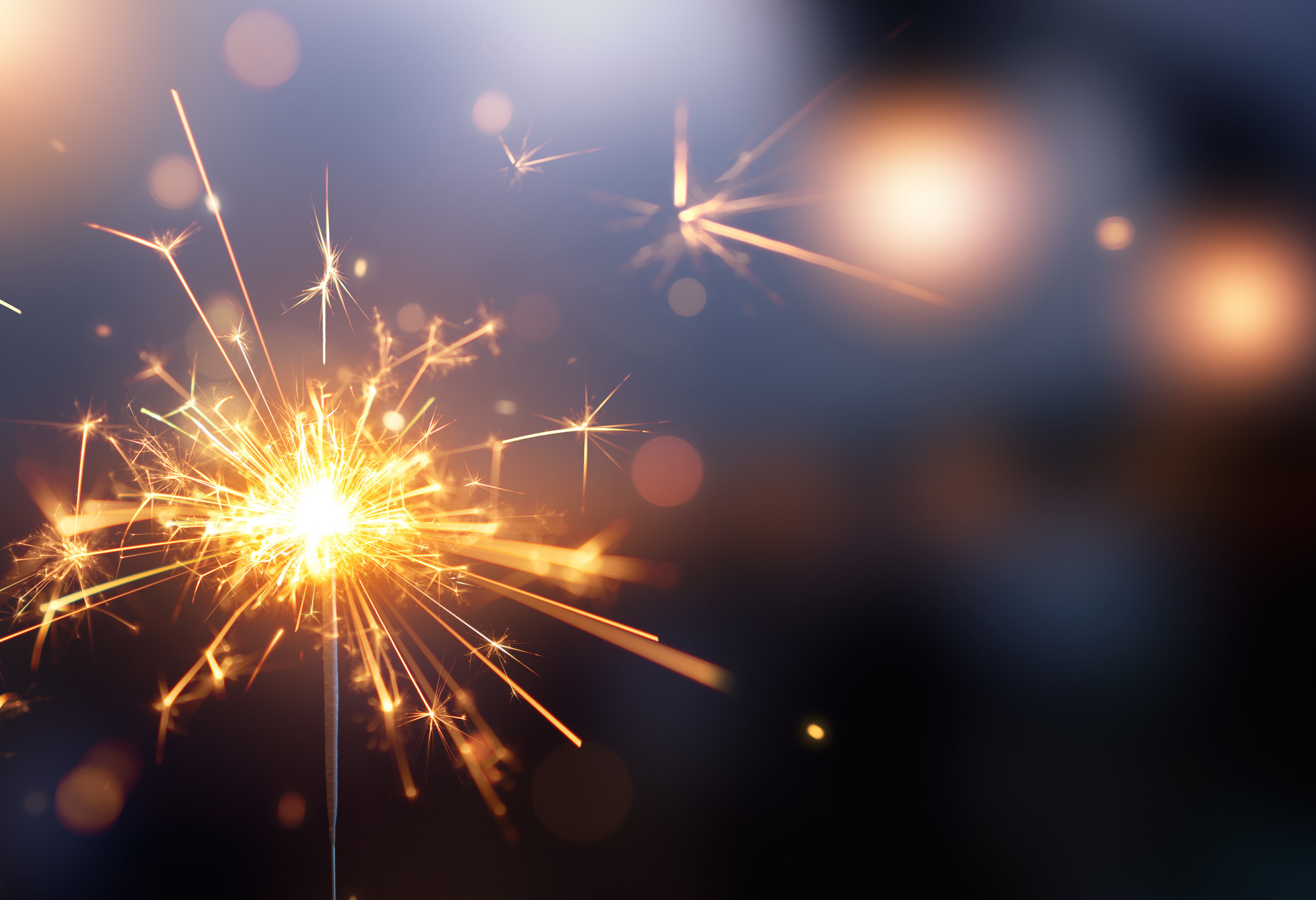 Glittering burning sparkler against blurred bokeh light background