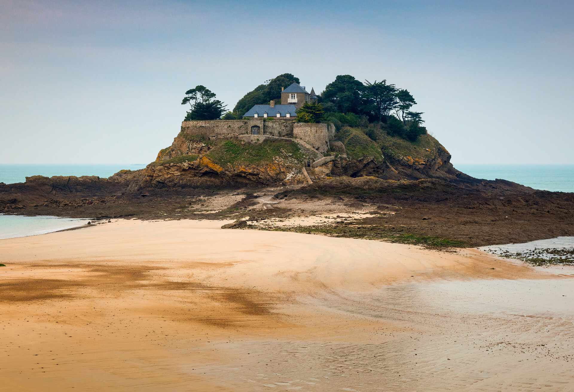 Beach landscape of a private island castle on a secluded beach on the northern emerald coastline of France. / Fort Guesclin Brittany France; Shutterstock ID 224857294