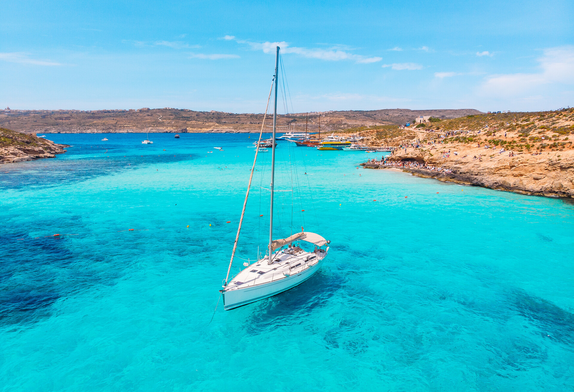 White yacht stands in azure transparent water sea, beach Blue Lagoon Comino Malta. Aerial view.; Shutterstock ID 1413619622; Purpose: Visit Malta project; Brand (KAYAK, Momondo, Any): KAYAK