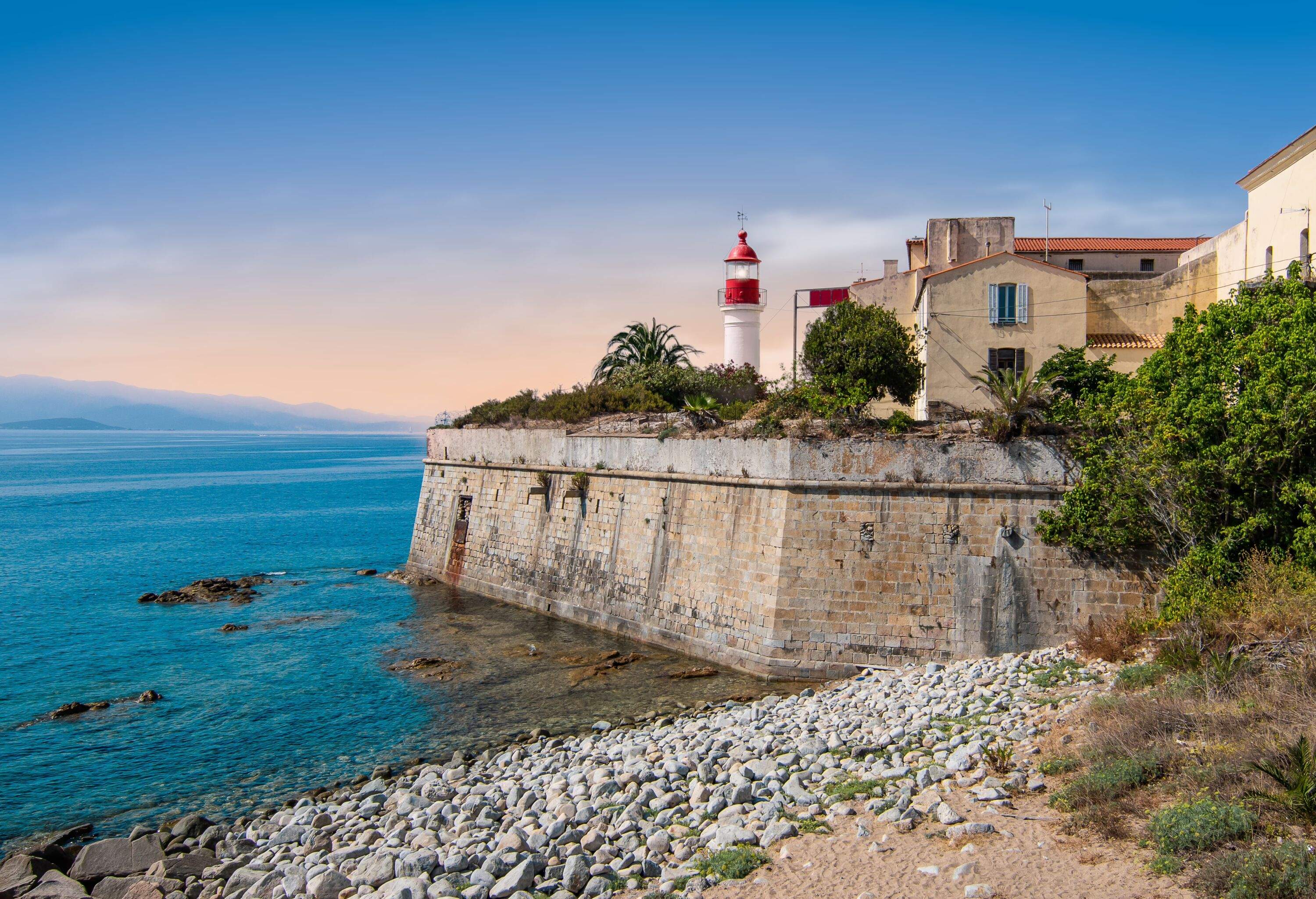 Bright horizontal image with lighthouse at citadel at the coastline, Corsica Island, France. Blue sky.