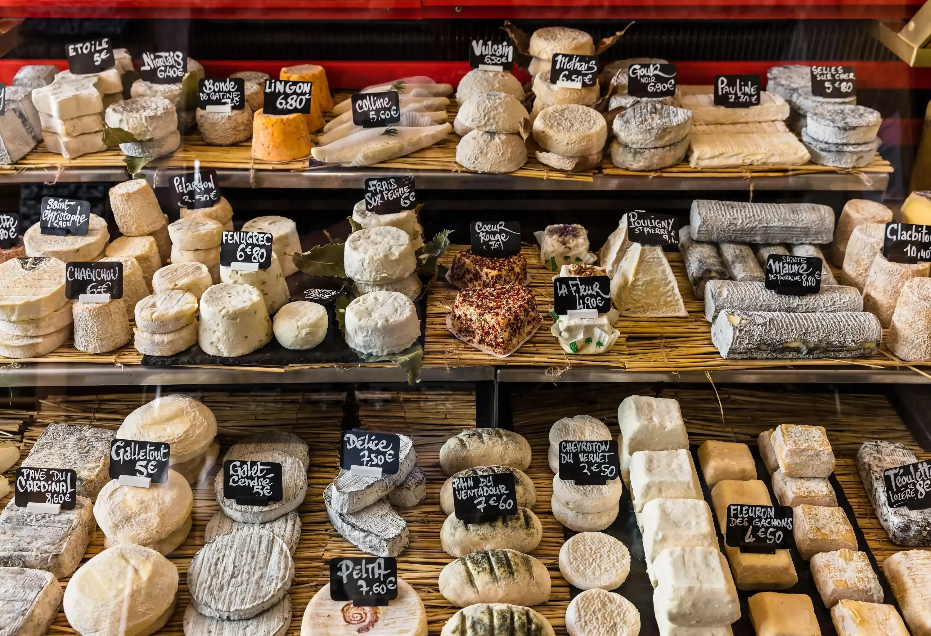A display of assorted cheese with individual labels and pricing.