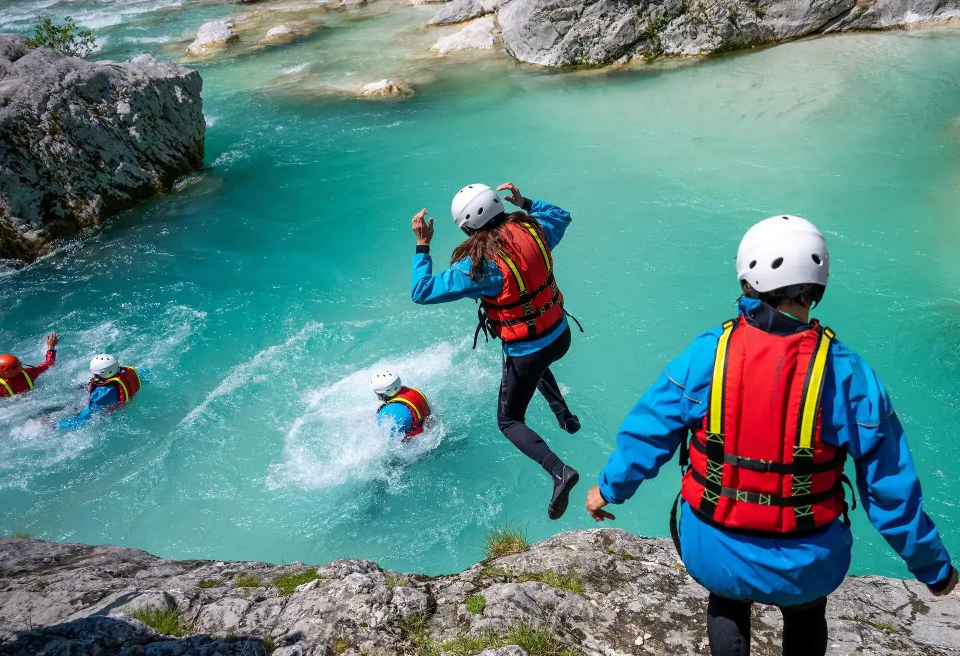 A group of people canyoning and jumping in the water