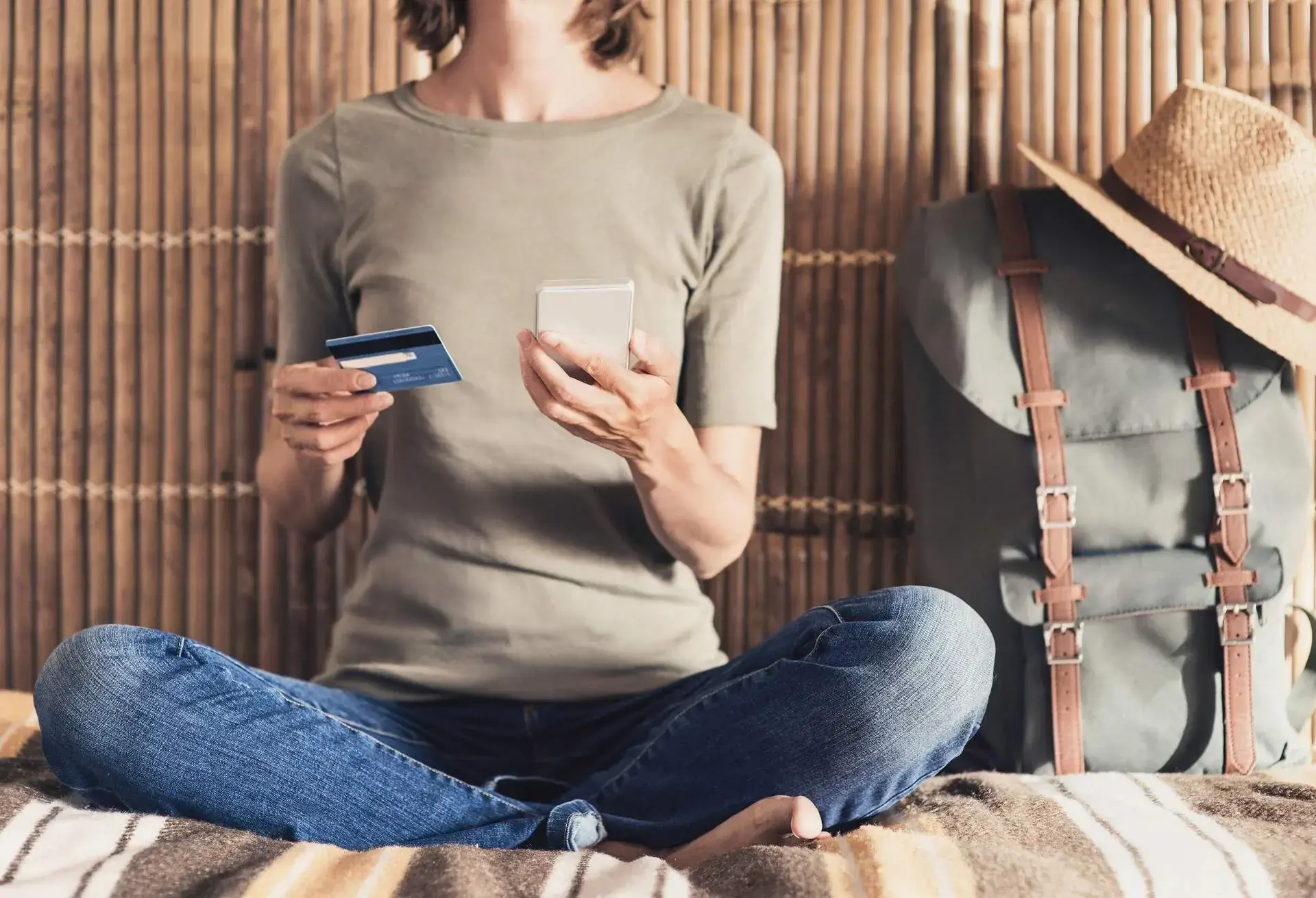 A woman sitting with her phone in her left hand, and her credit card in the right hand