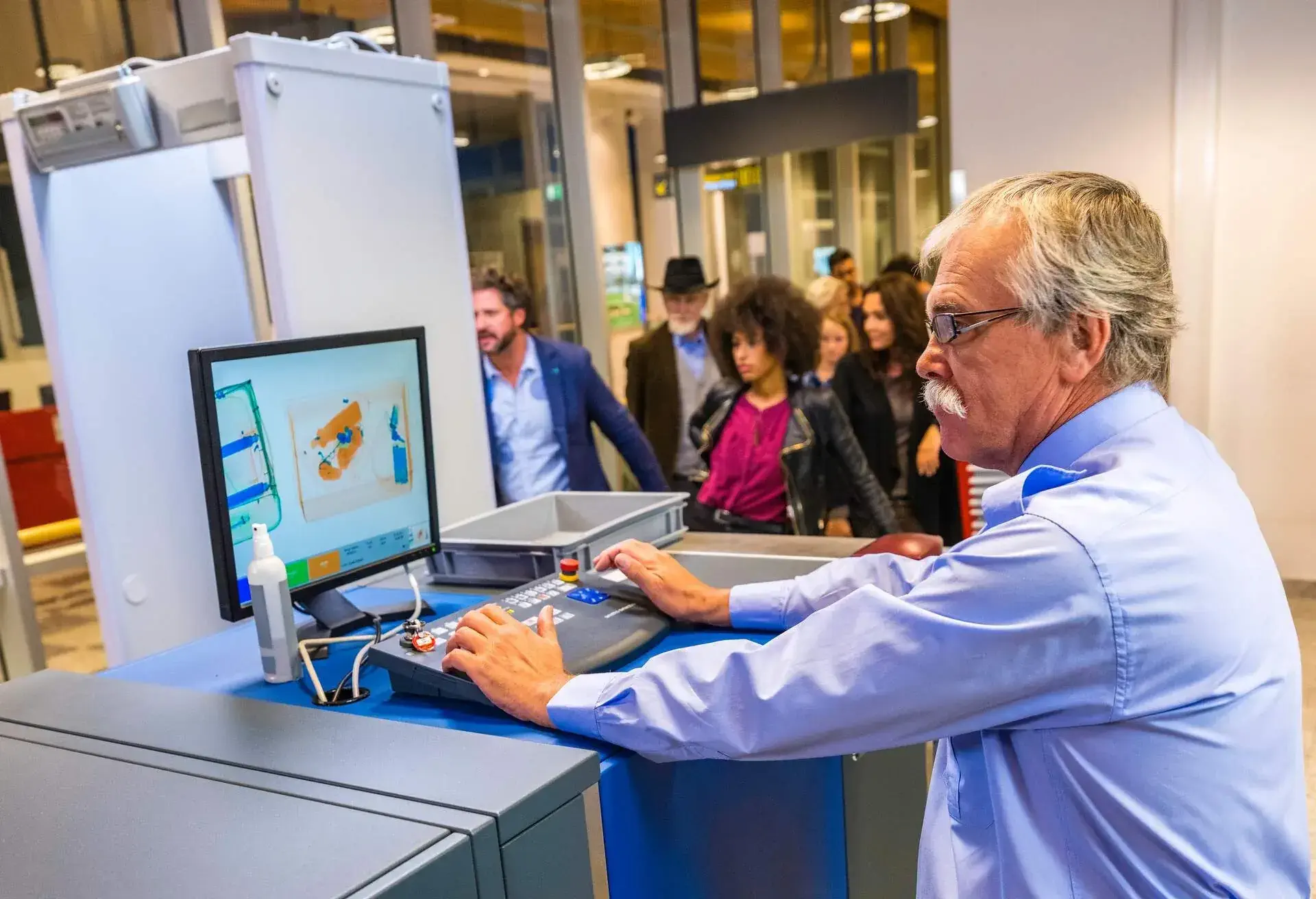 A man scanning bags at an airport security check