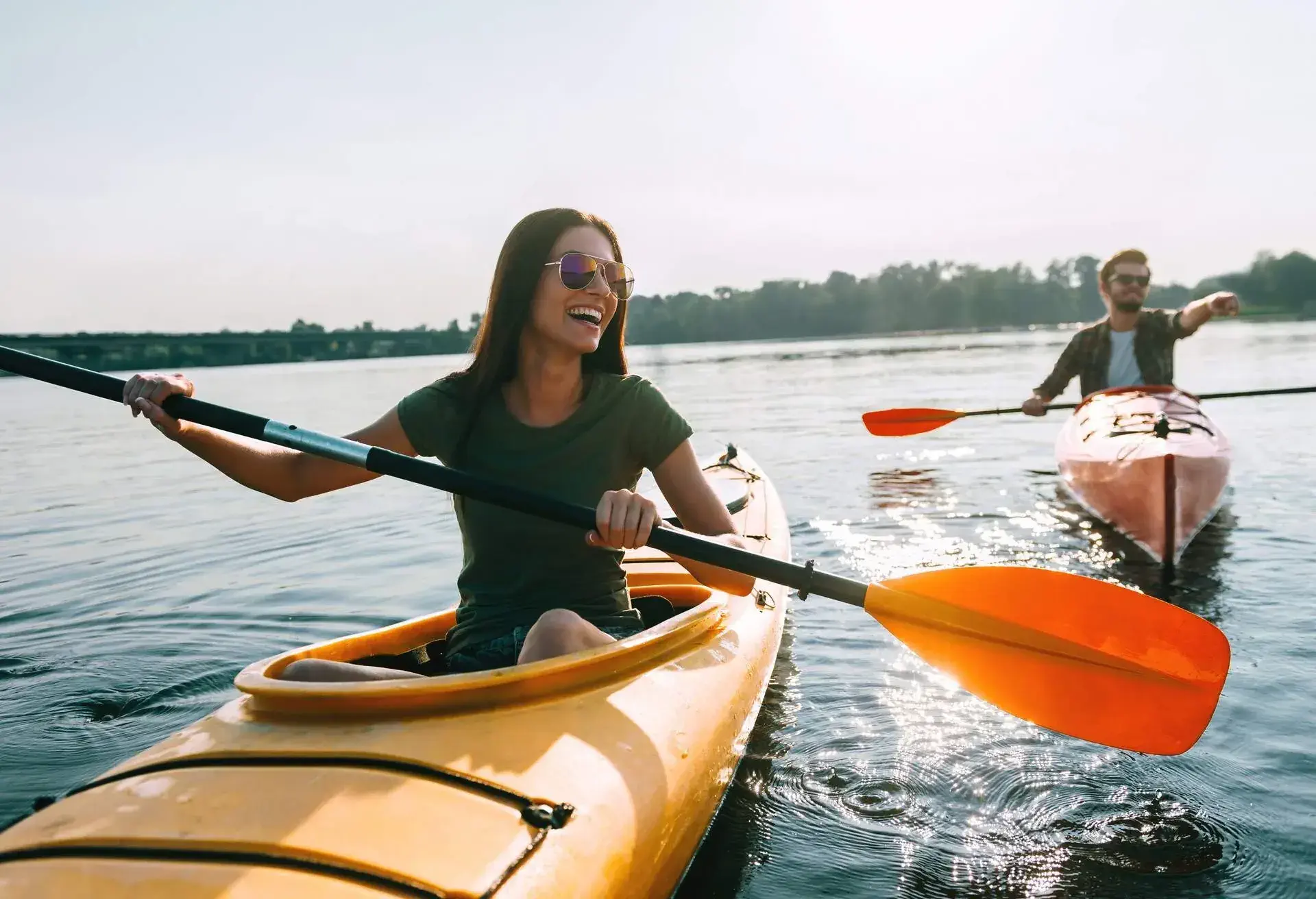 Beautiful young couple kayaking on lake together and smiling 