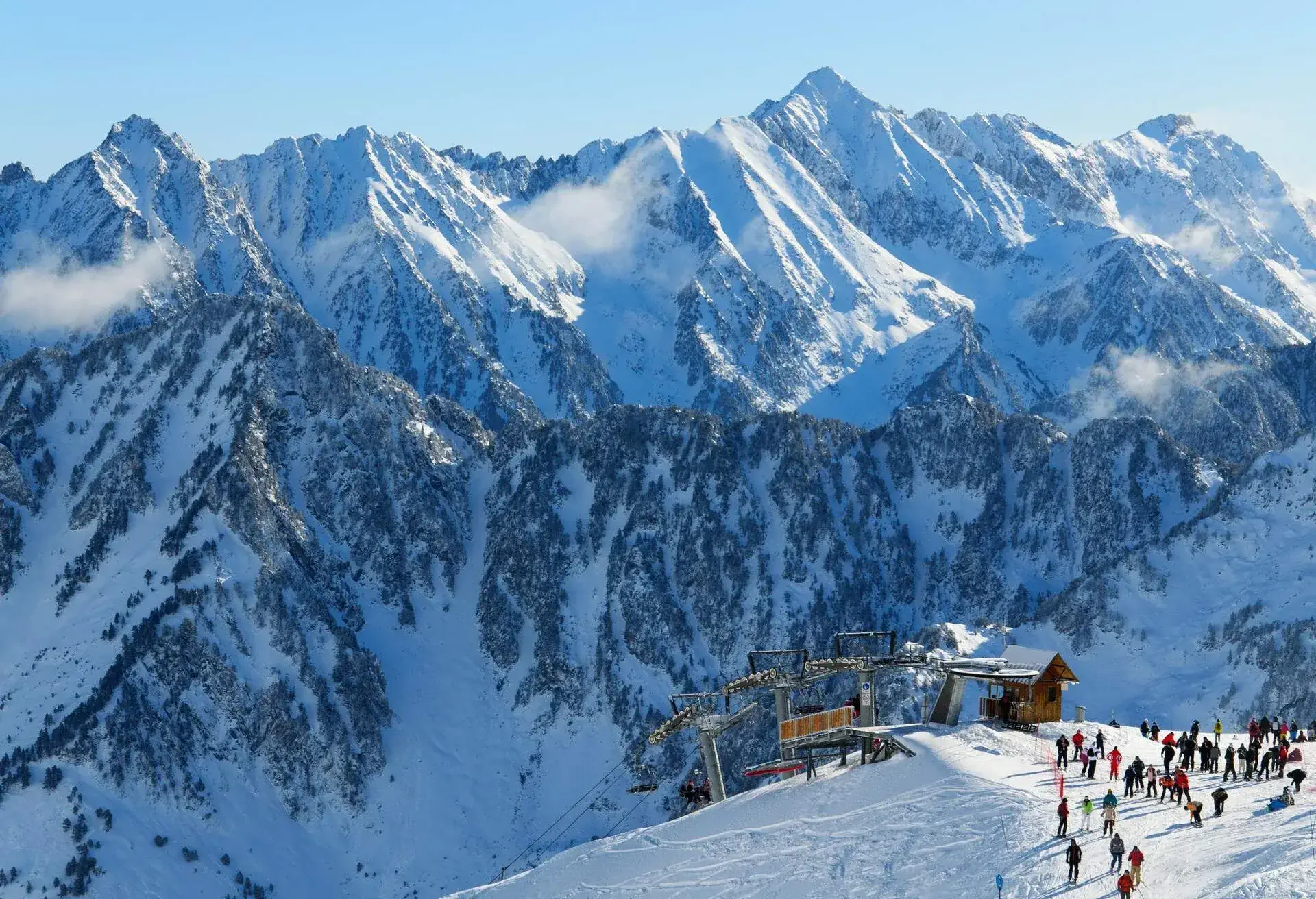 Pyrénées en hiver photographiées au domaine skiable de Cauterets avec des skieurs transportés par le télésiège Grand Barbat sur les pistes enneigées du Cirque du Lys et la chaîne de montagnes (Soum de Mauloc) en arrière-plan.