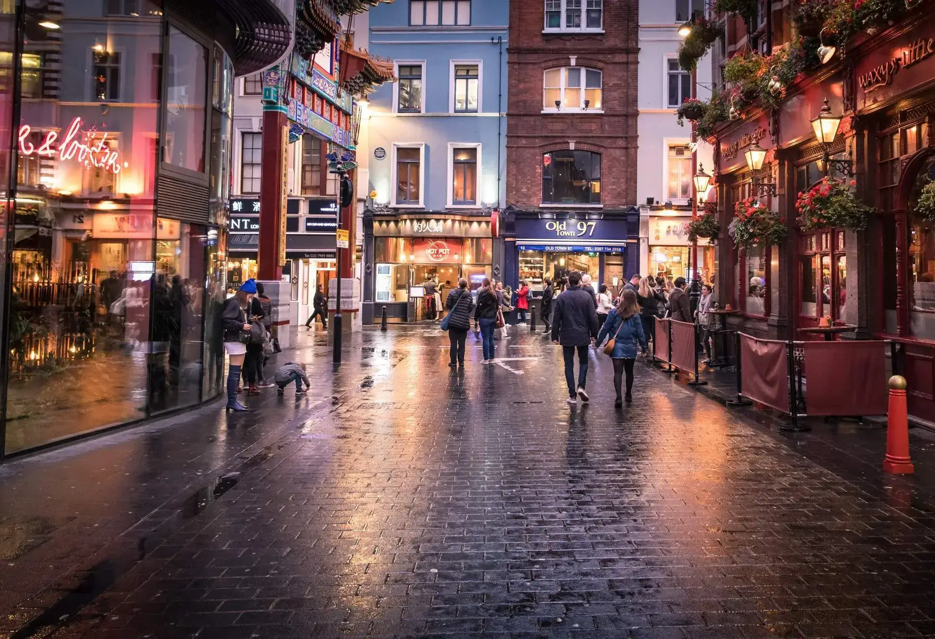 a street in London's Soho district in the evening as the lights come on