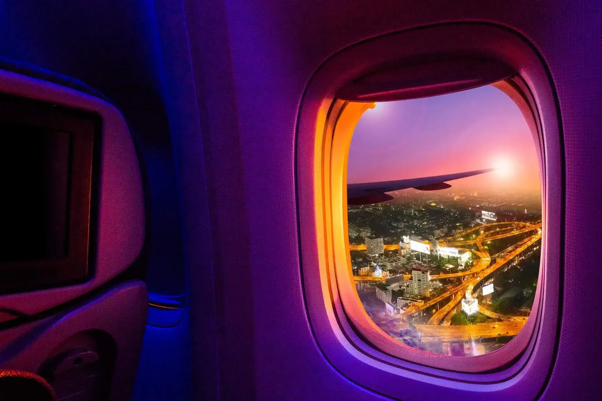 Illuminated bustling streets across the city viewed through the airplane's window.