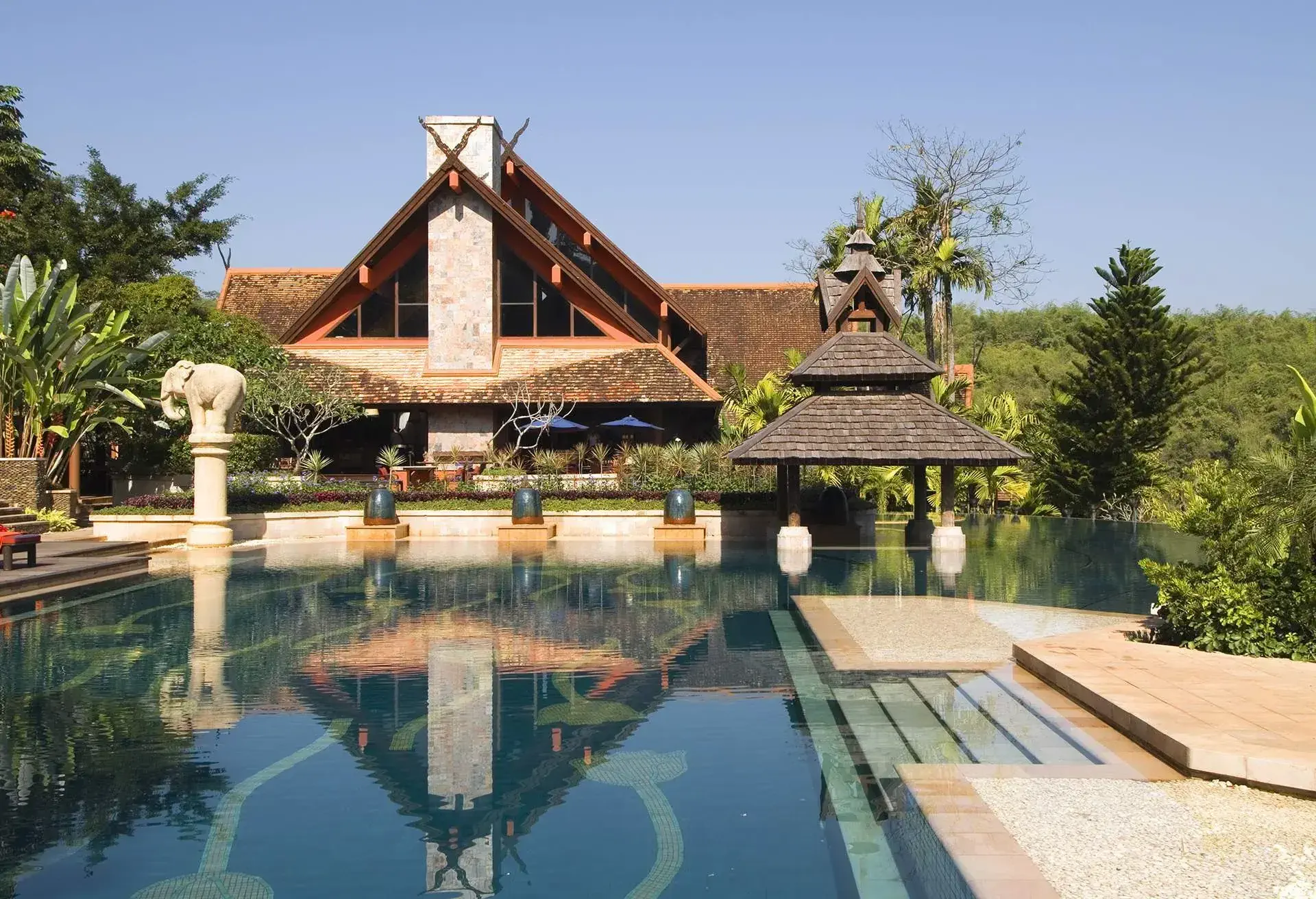 A photo of a resort hotel in Thailand with a swimming pool in front of it.