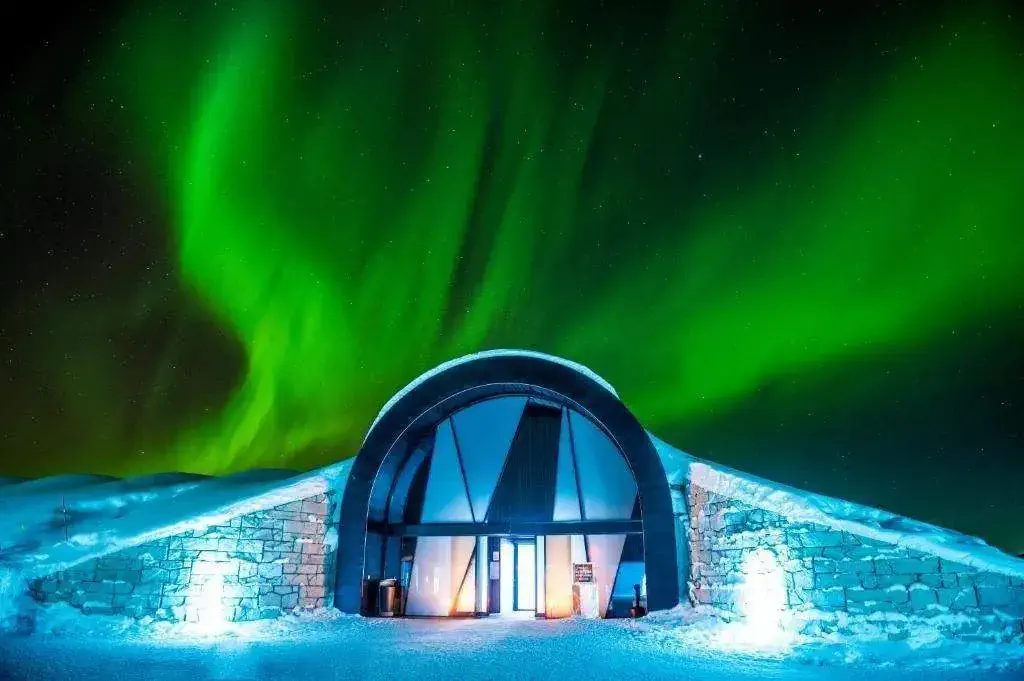 A hotel entrance covered in snow with aurora borealis on the night sky