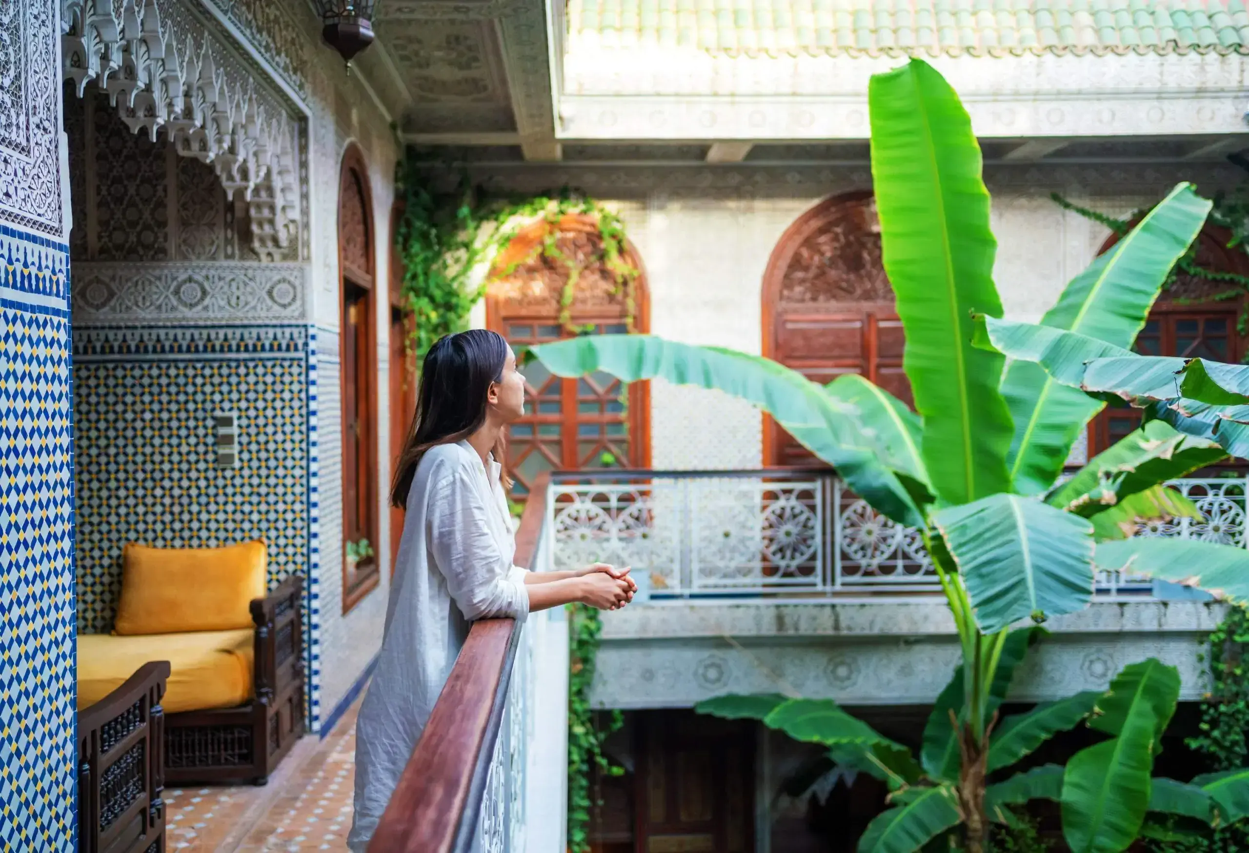 A female tourist deep in thought leans her arms on the balcony.