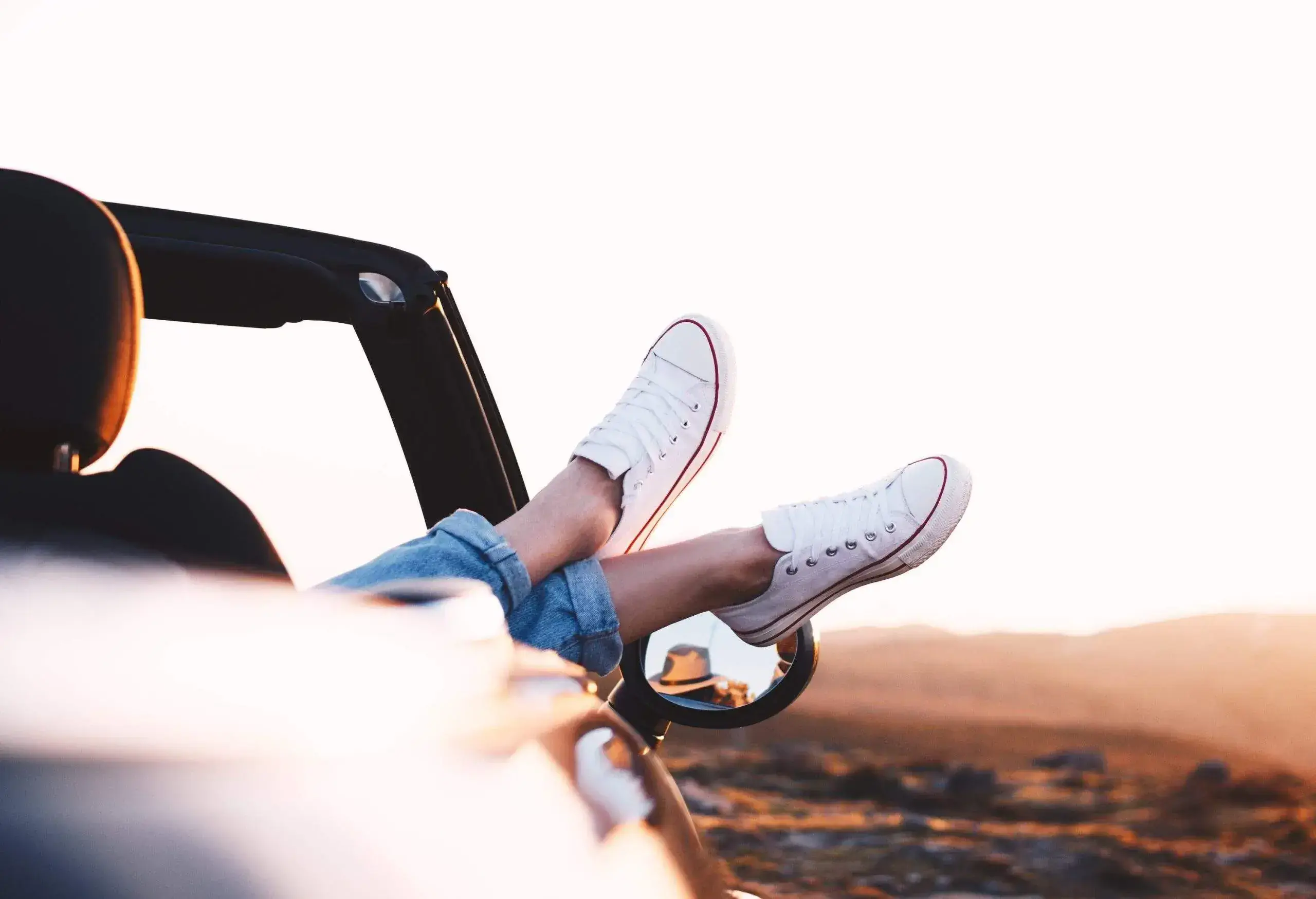 A person with their legs on the side of a convertible car