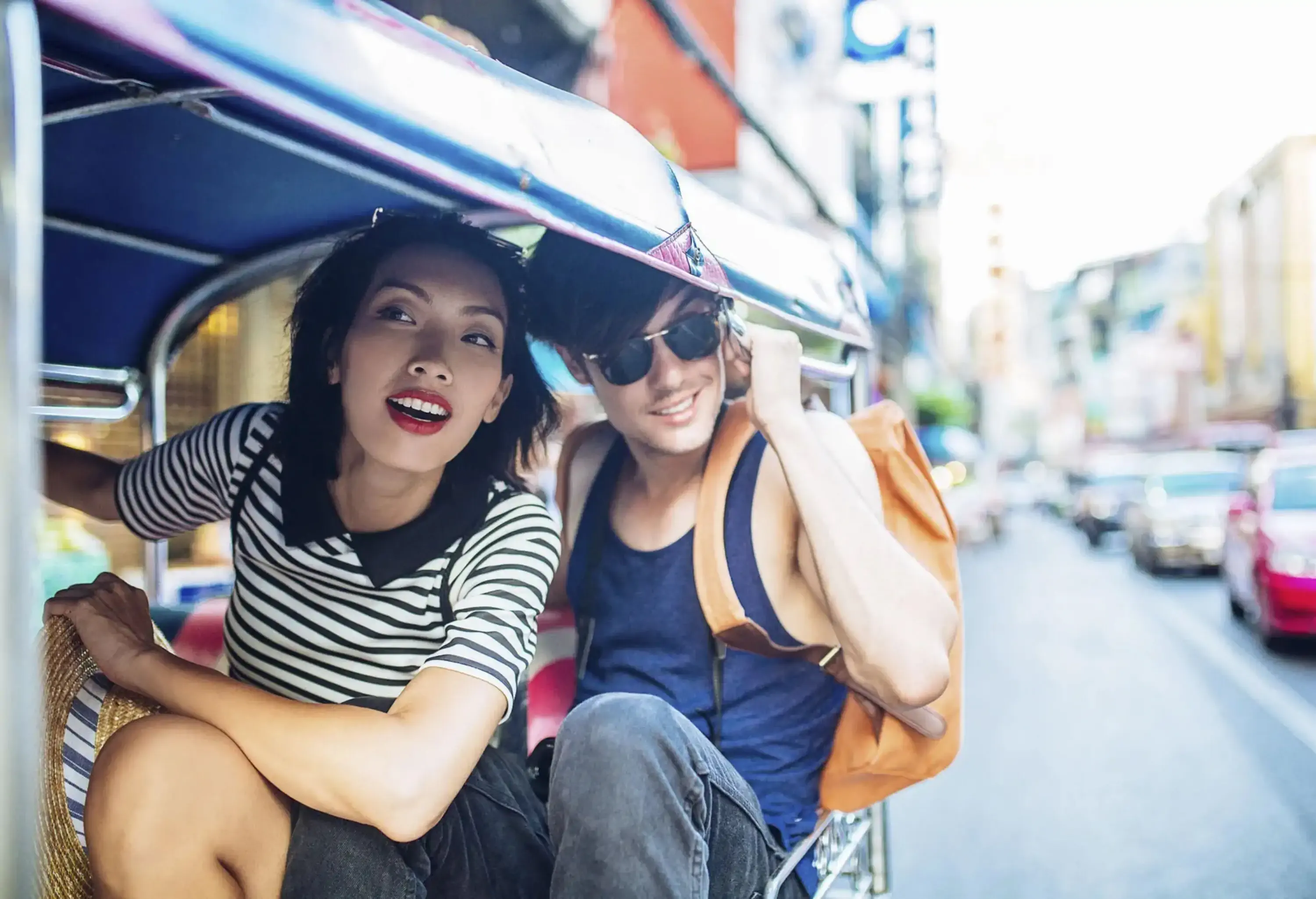 A couple in casual clothes enjoy riding a tuk tuk while admiring the views.