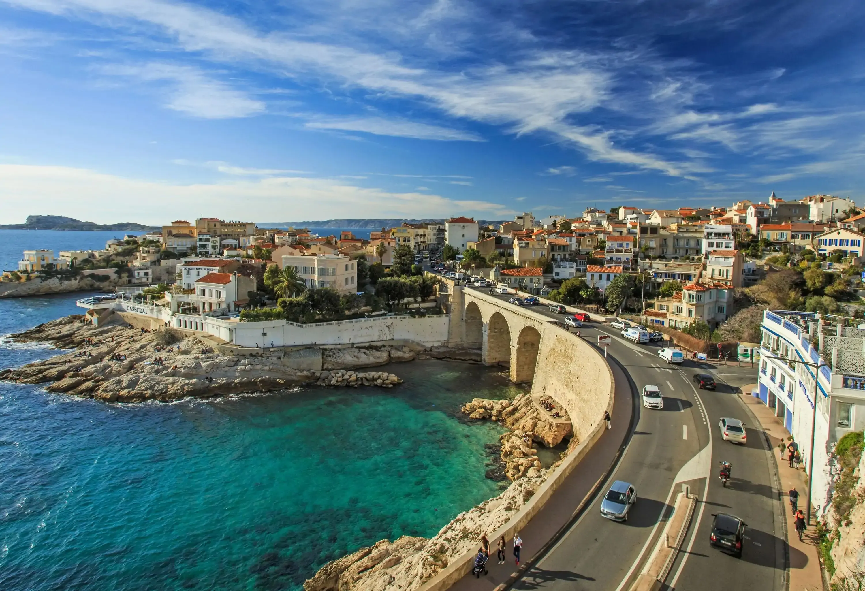 A stone bridge across a small bay along a coastal neighbourhood.