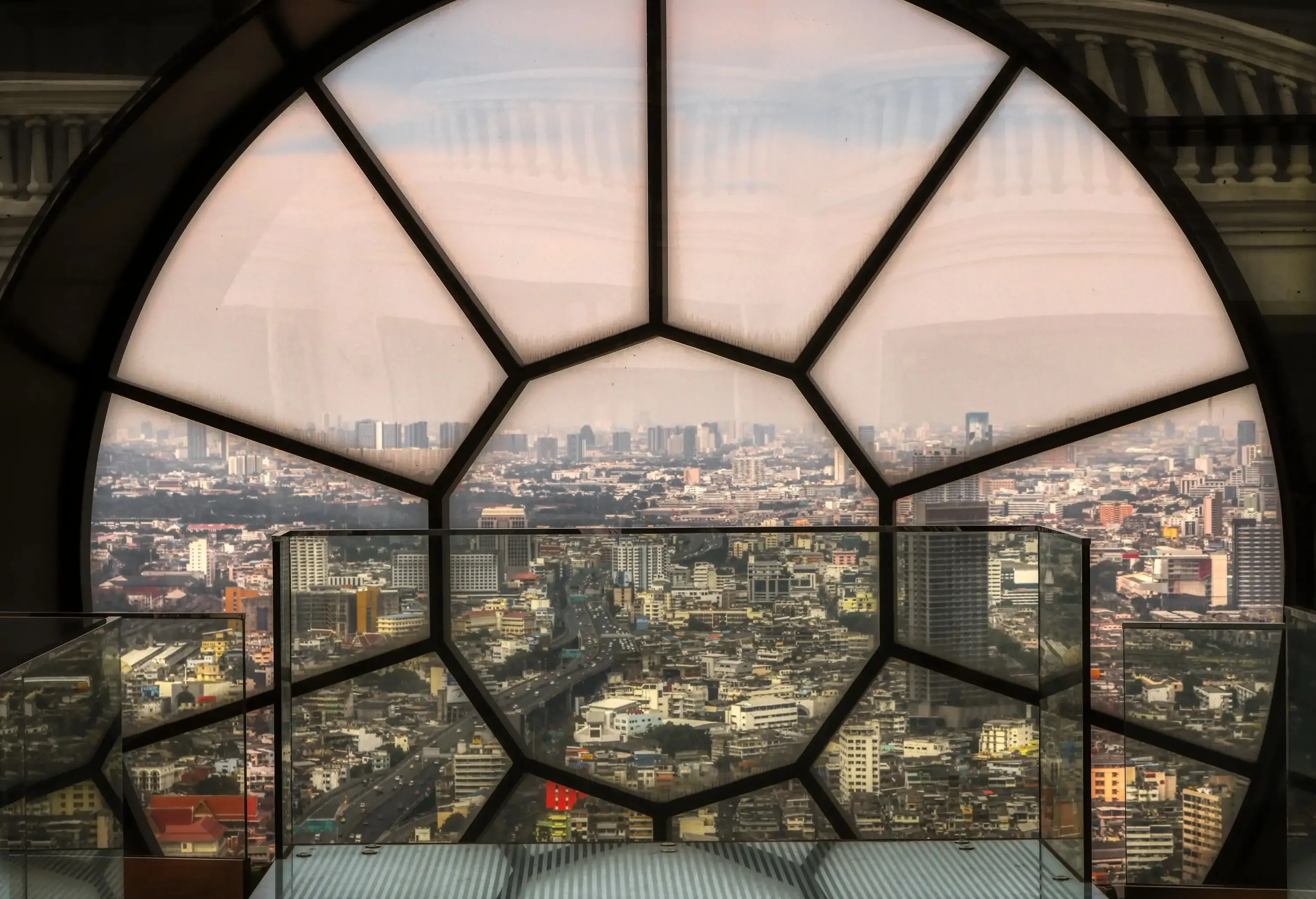 The urban cityscape is seen through a decagon-shaped artistic glass pane.