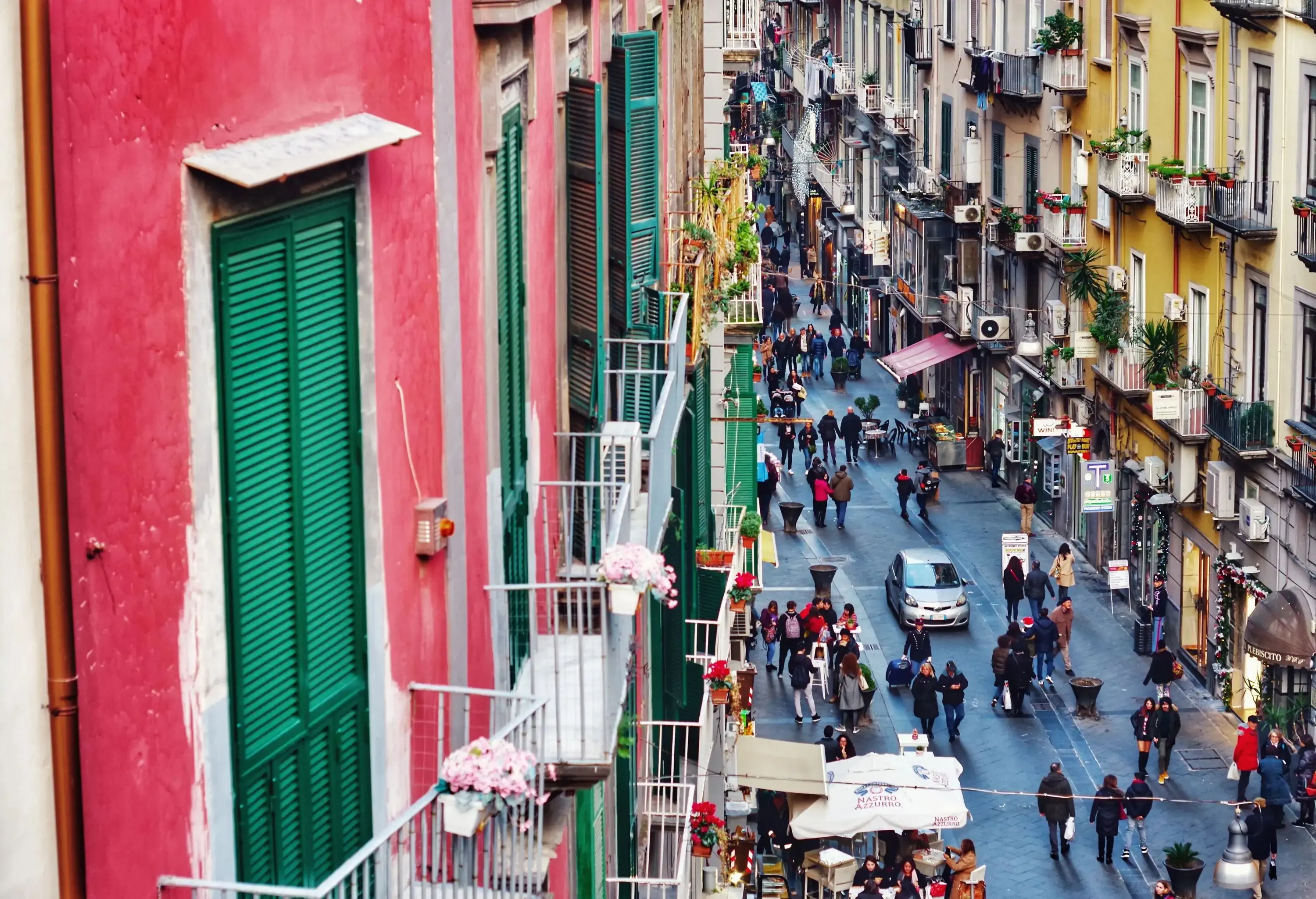 A lively shopping street lined with colourful shops with cute window balconies.