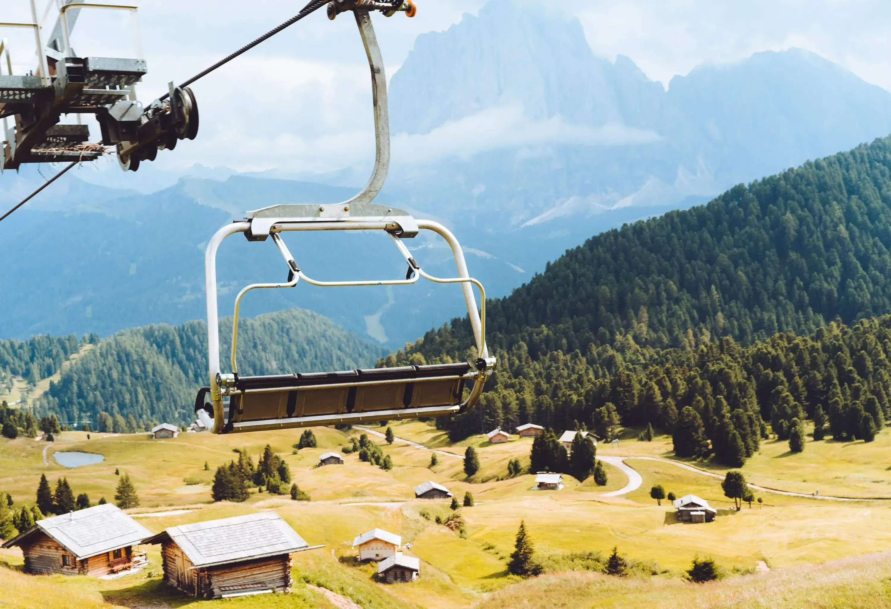 A photo of a ski chair lift in the Dolomite mountains on a summer day.
