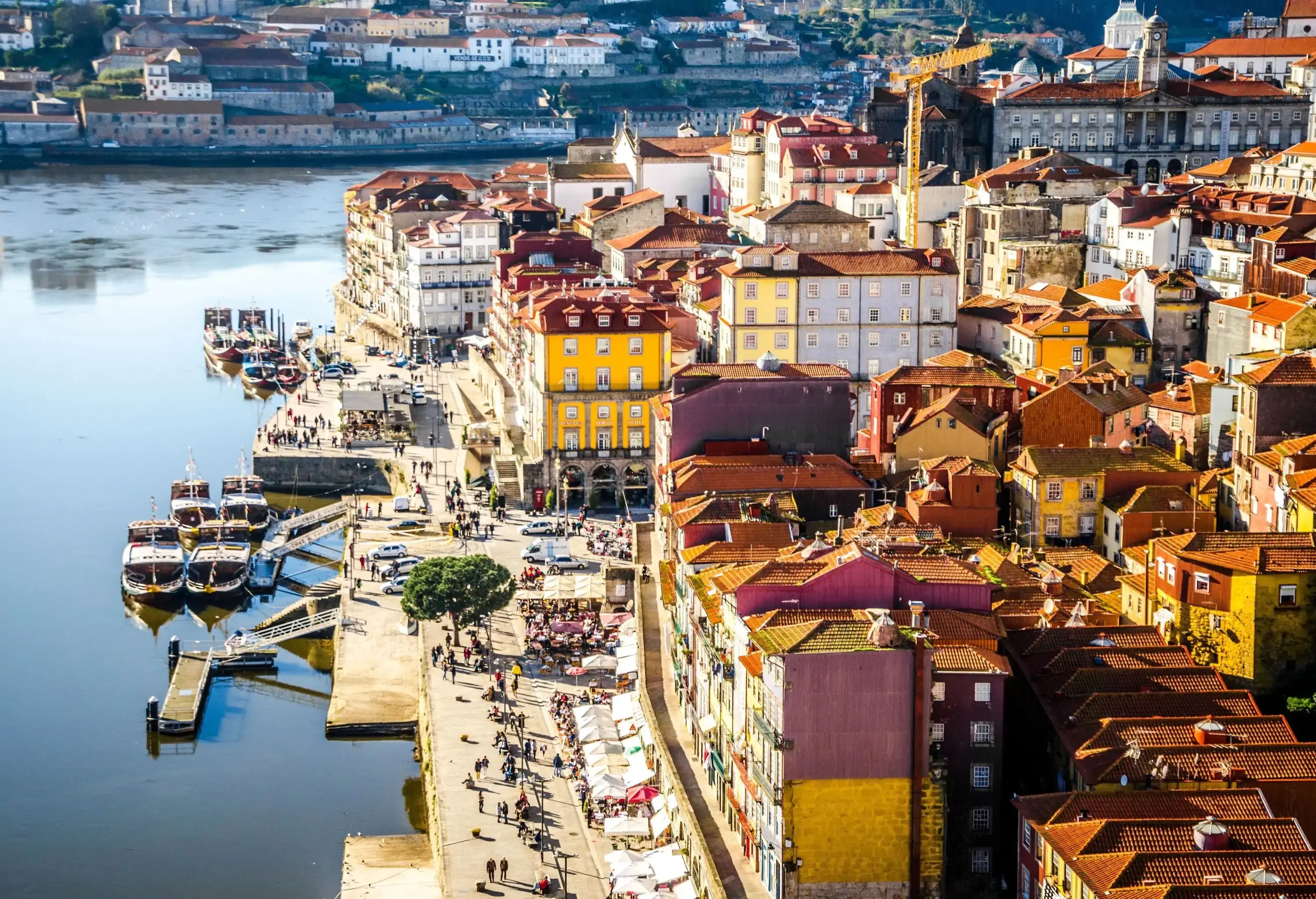 A bustling harbourfront promenade lined with brightly coloured historic structures.
