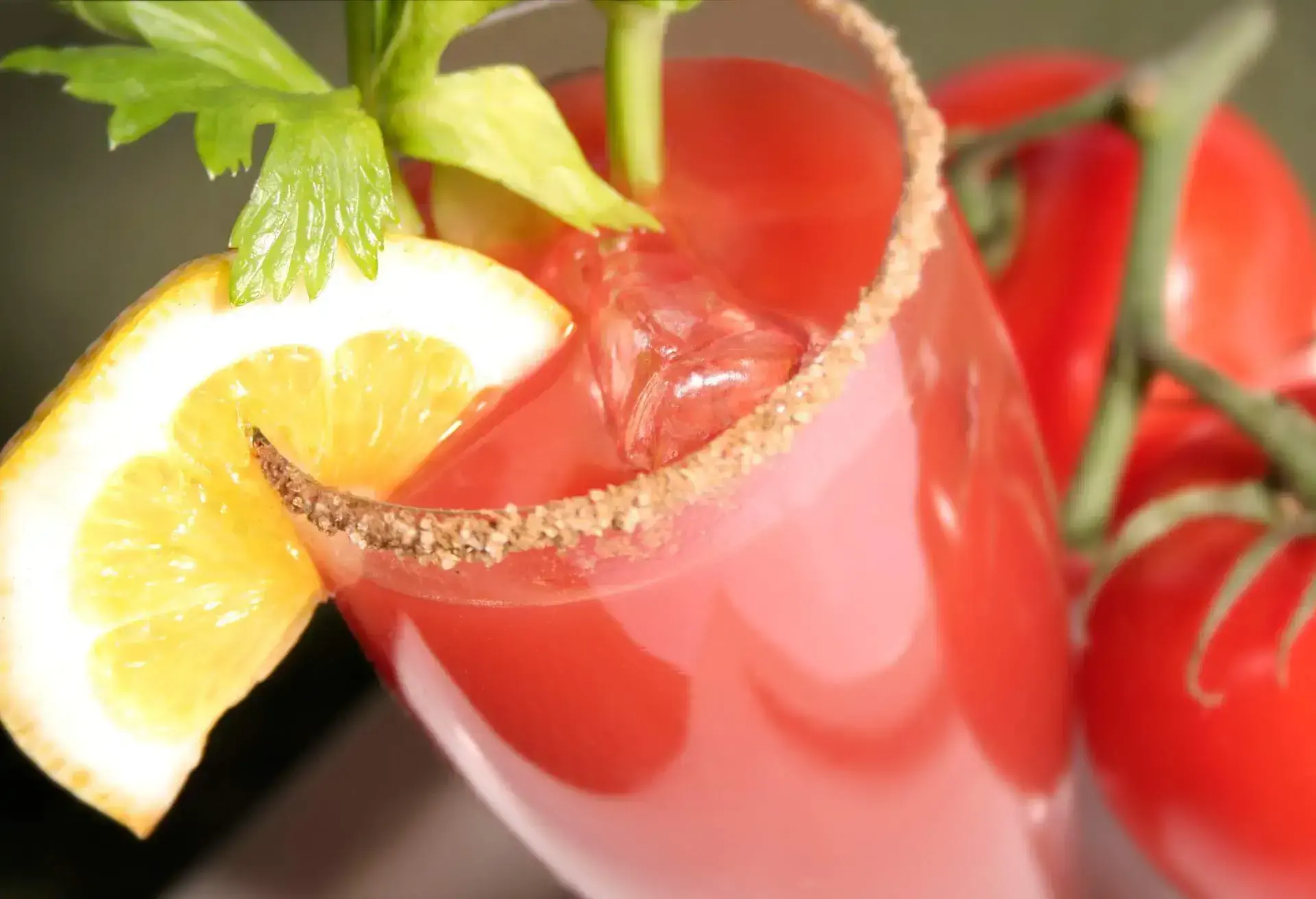 Caesar Cocktail in a class with lemon slice and two tomatos next to the glass
