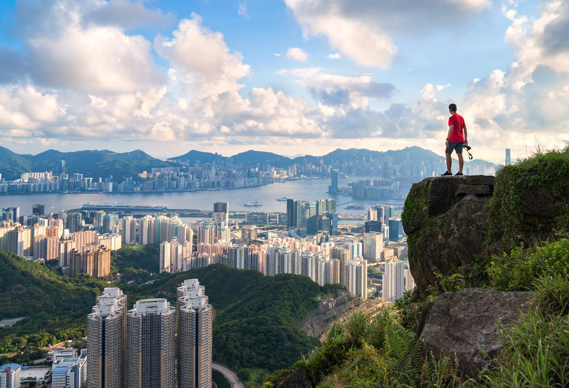 photographer standing on the top of Cliff above Hong kong cityscape