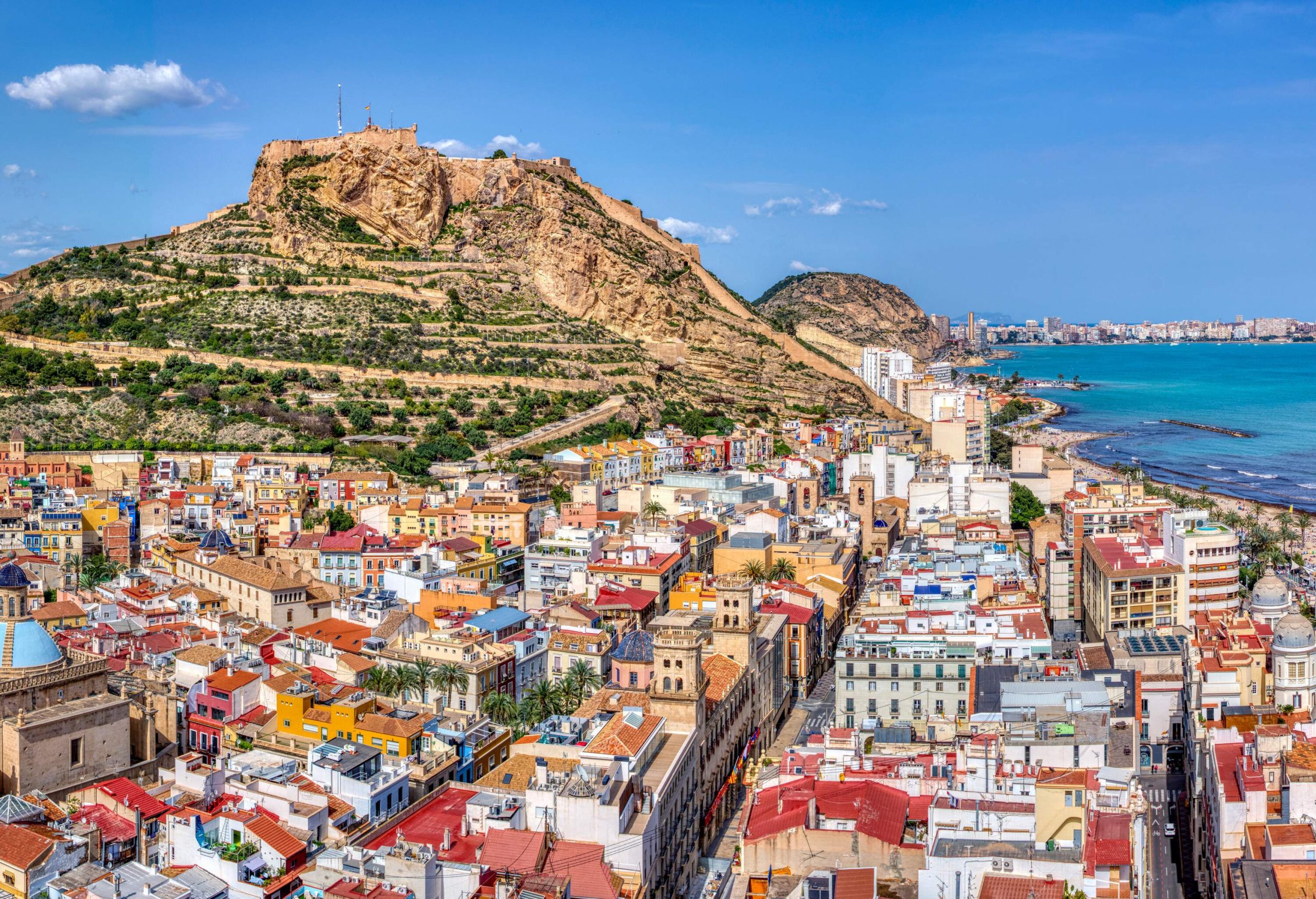 A densely populated beach town with multicoloured buildings dotting the shore.