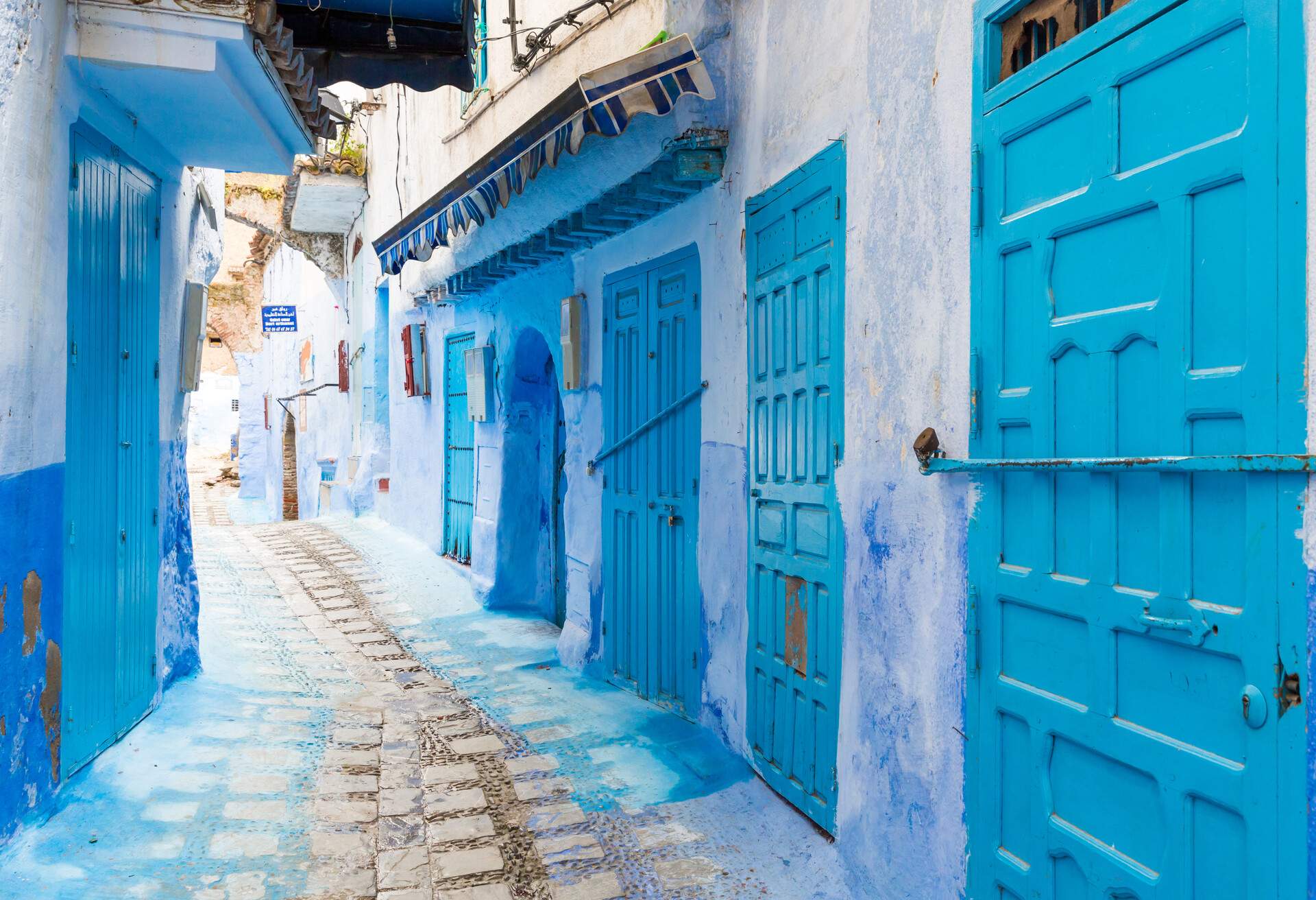 A cobbled alleyway in the middle of compact blue-washed houses.