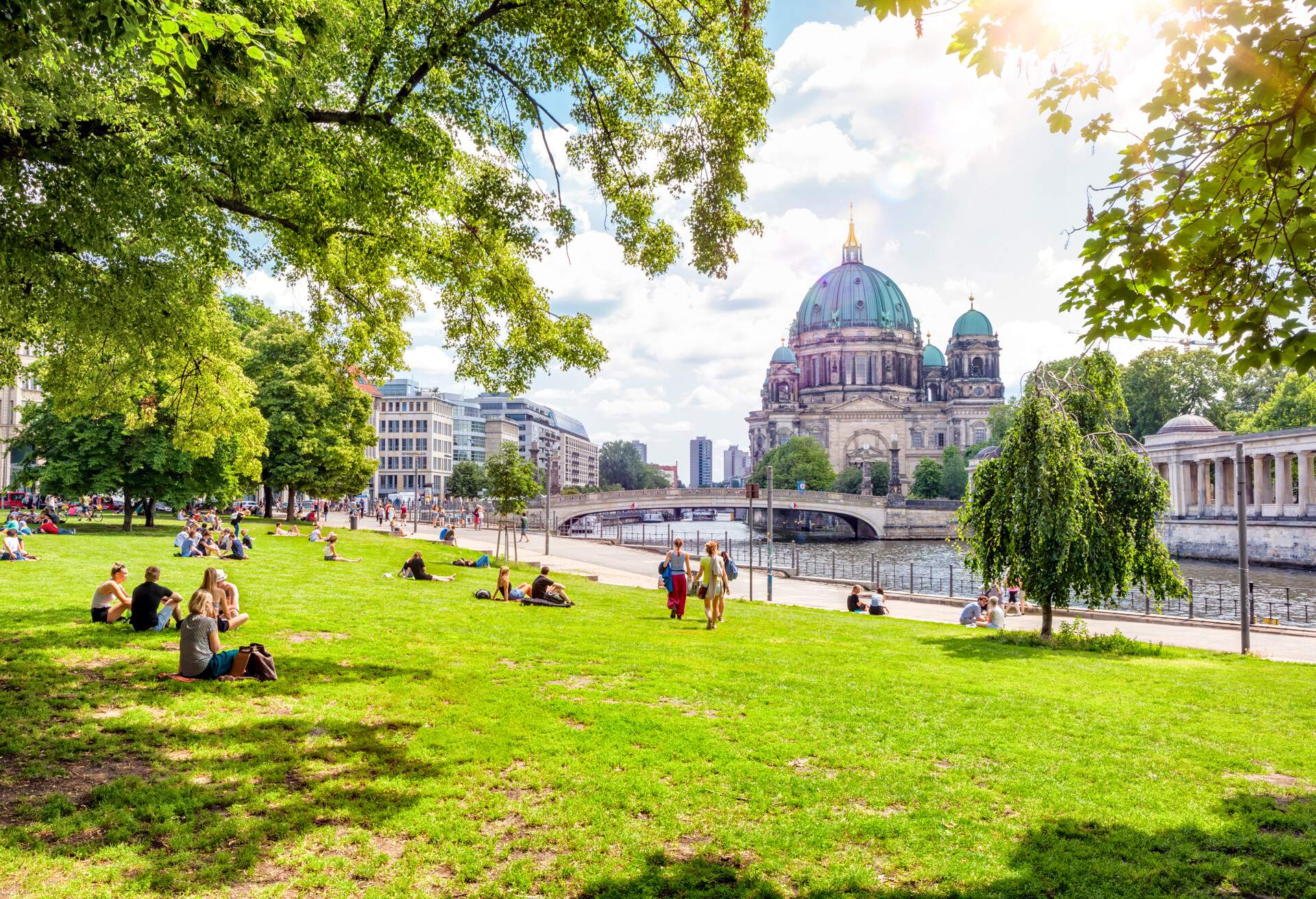 People relaxing on a lawn. The Berliner Dom (Berlin Cathedral) can be seen across the Spree river - Berlin, Germany