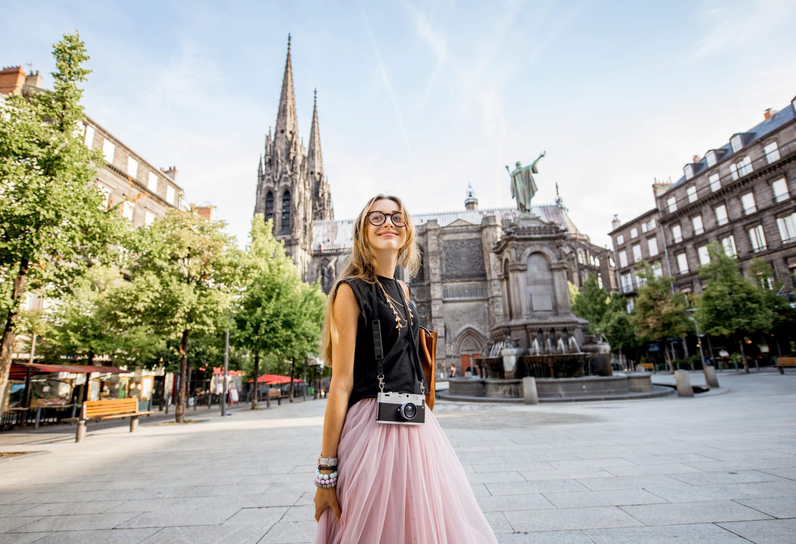 Lifestyle portrait of a woman traveling in front of the famous cathedral in Clermont-Ferrand city in France