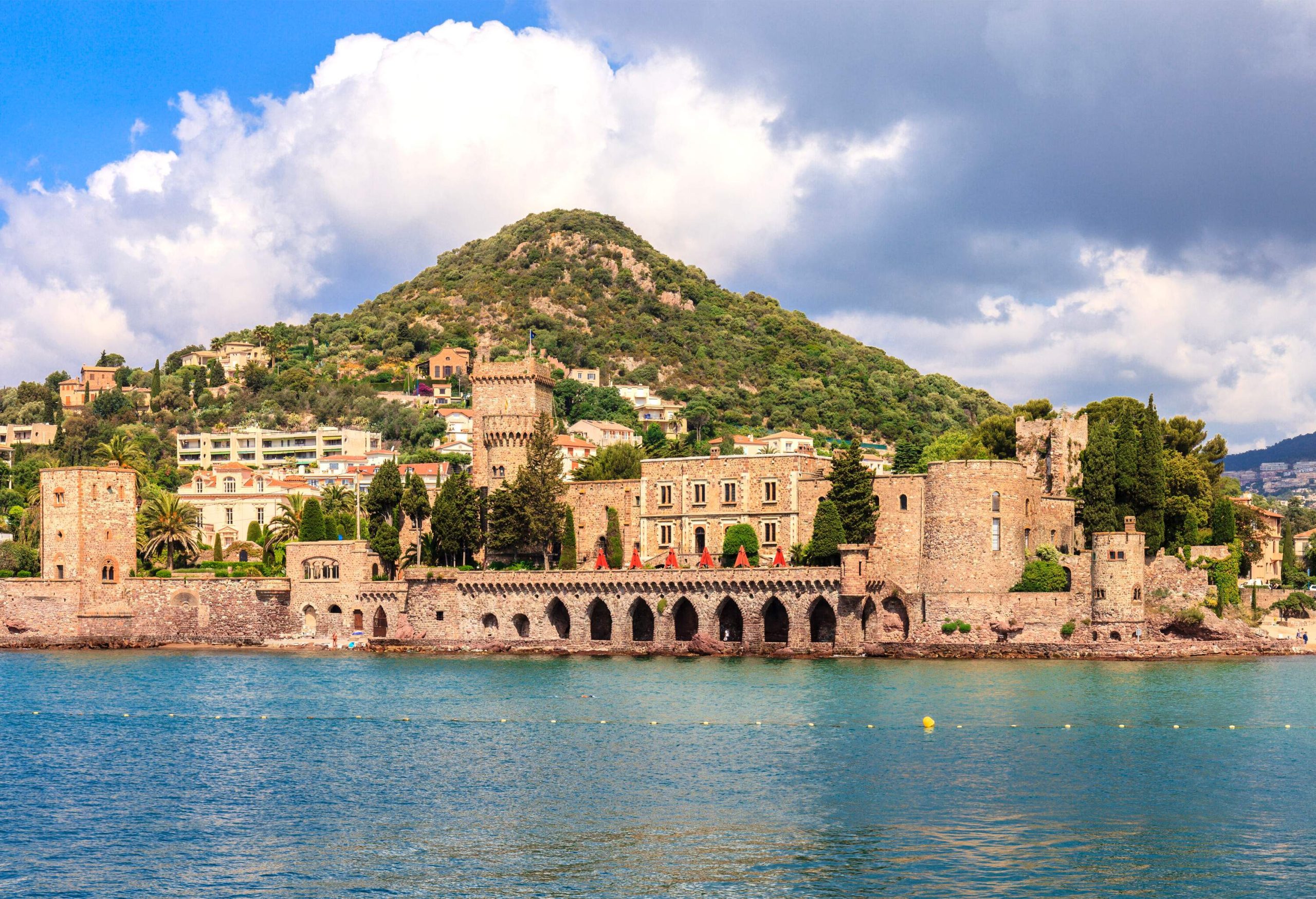 View of a castle by the shore with mountain in the background on a summer day