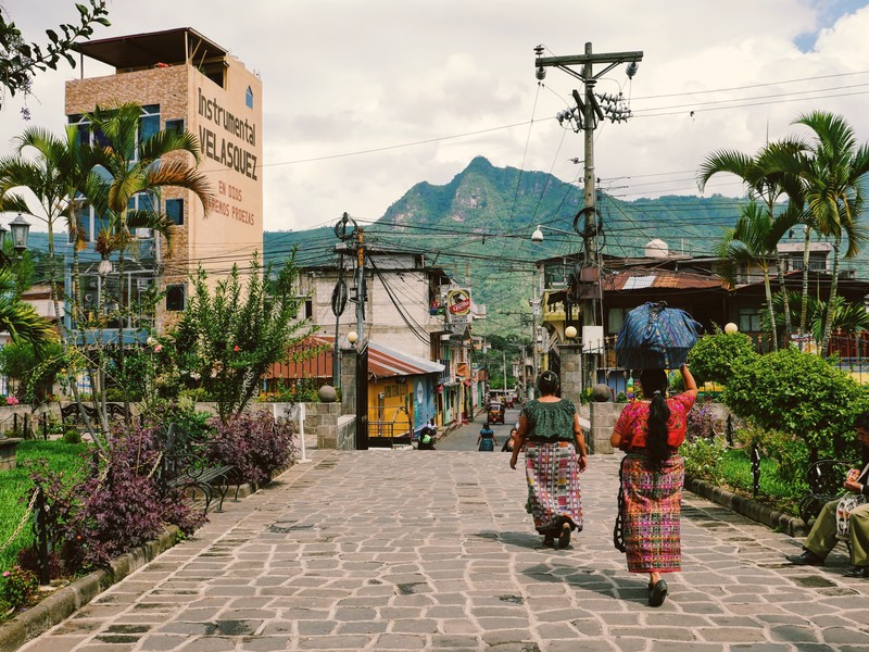 Deux femmes se baladent dans une rue au Guatemala et on aperçoit les montagnes volcaniques en arrière-plan