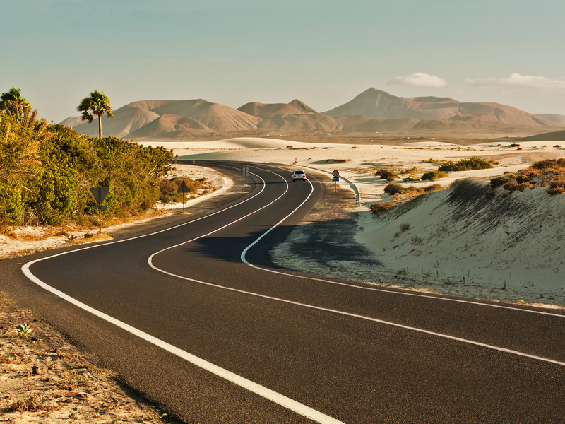 Une route déserte sinue à travers les montagnes de sable de Fuerteventura