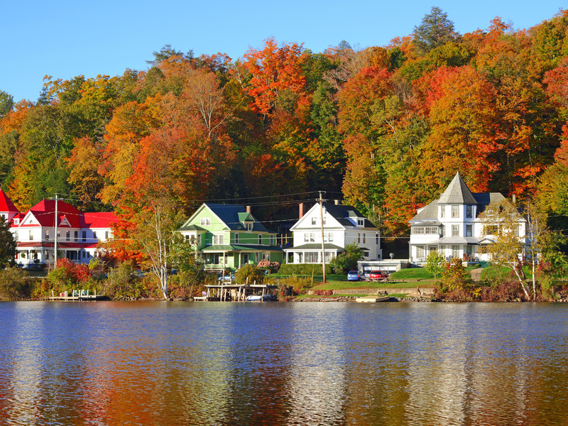 De belles maisons au bord d'un lac avec la forêt en arrière-plan qui commence à rougir et revêtir ses couleurs d'automne dans les Adirondacks au États-Unis
