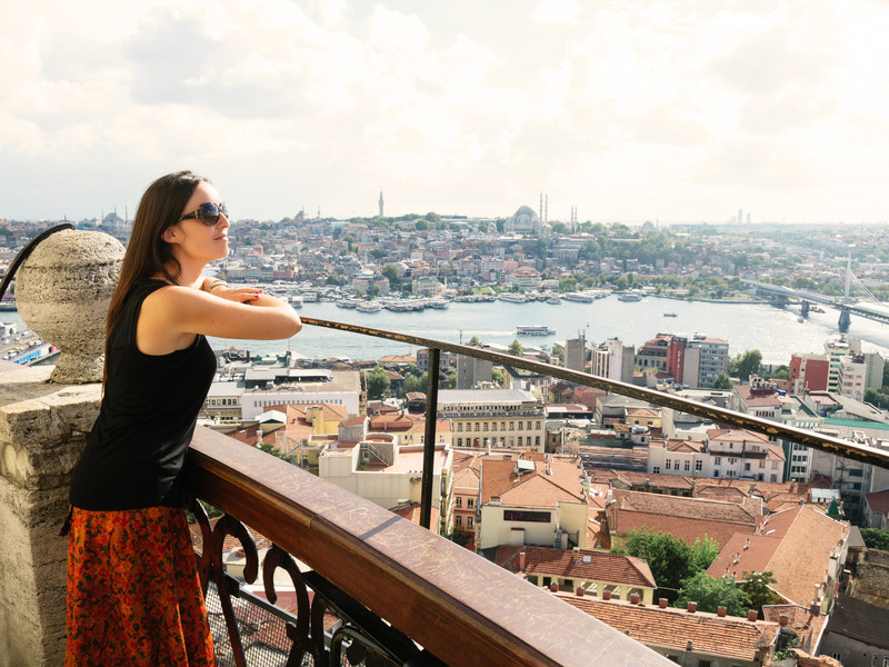 Beautiful woman leaning out  the Galata tower enjoying the amazing view of Istanbul, Turkey.