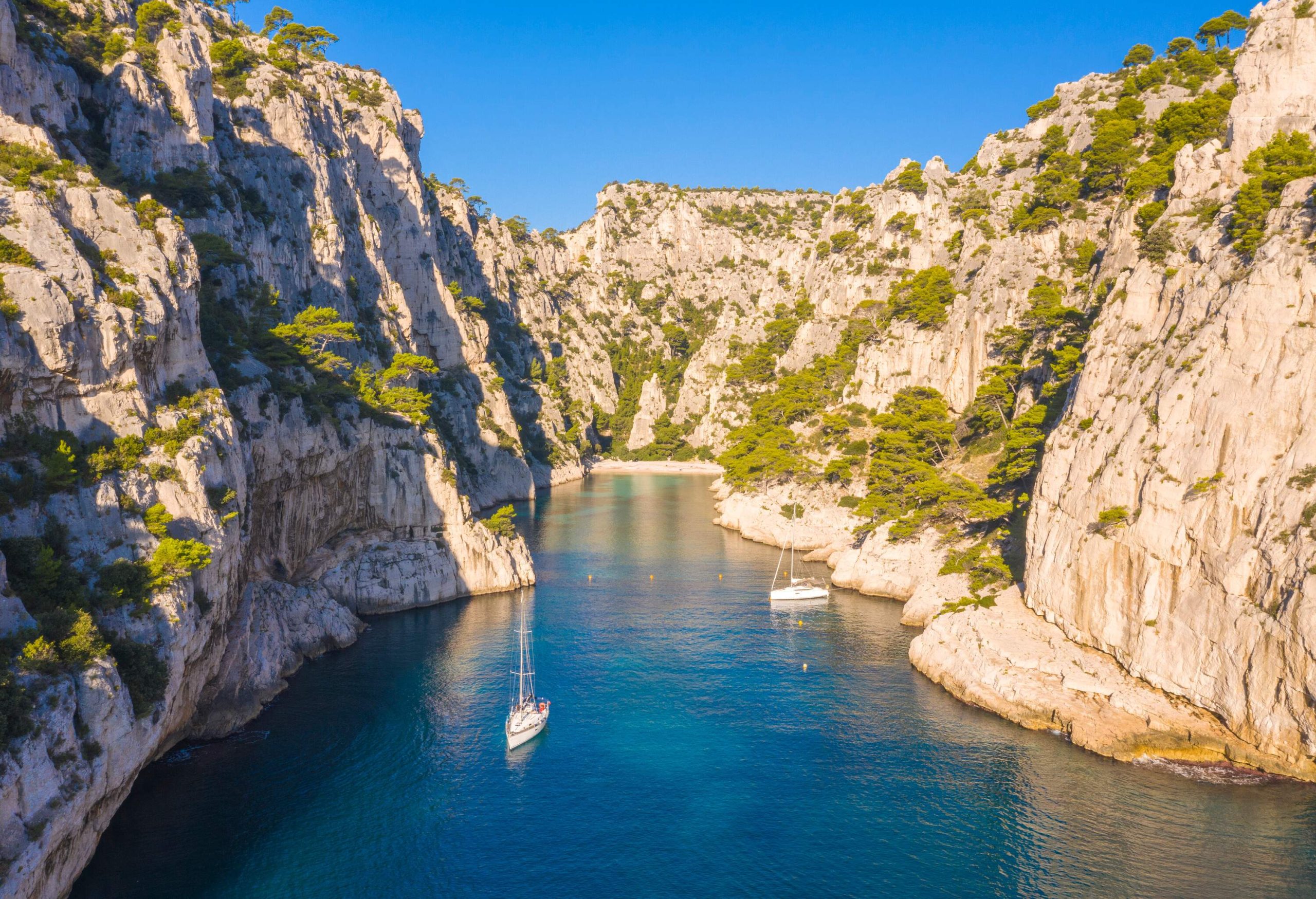 A picturesque view of white boats in the turquoise water cliff cove.