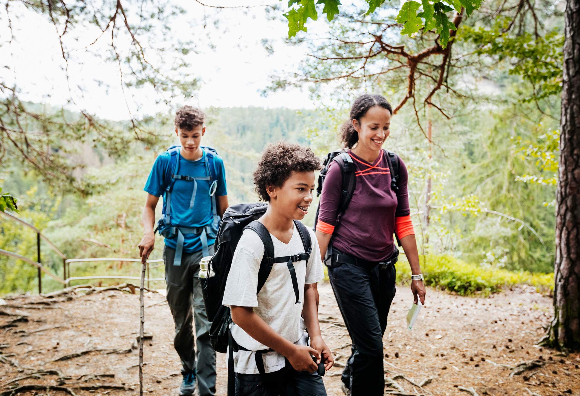 A woman and her two sons hiking in the mountains.