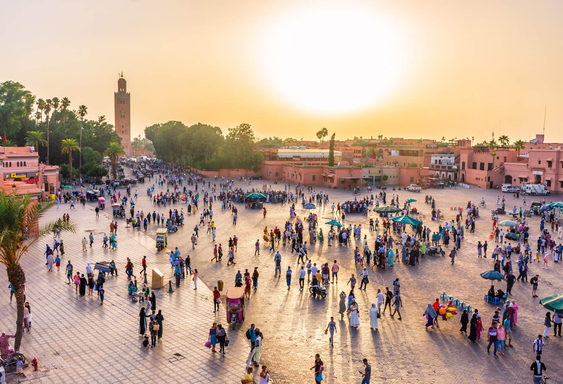 A market square crowded with travellers and locals at sunset.