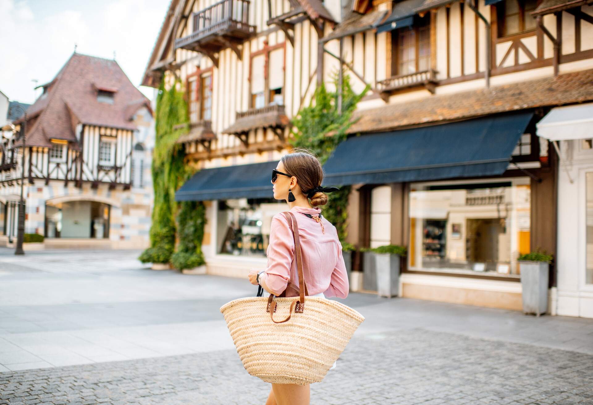 A female walks in a cobbled street lined with typical half-timbered houses and buildings in an old town.