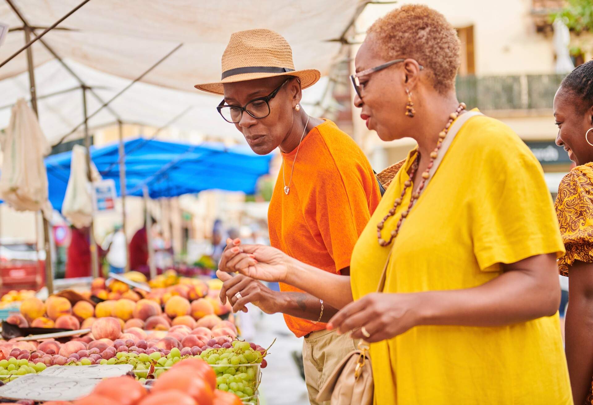 Female tourists on an outdoor market buying some fruits.