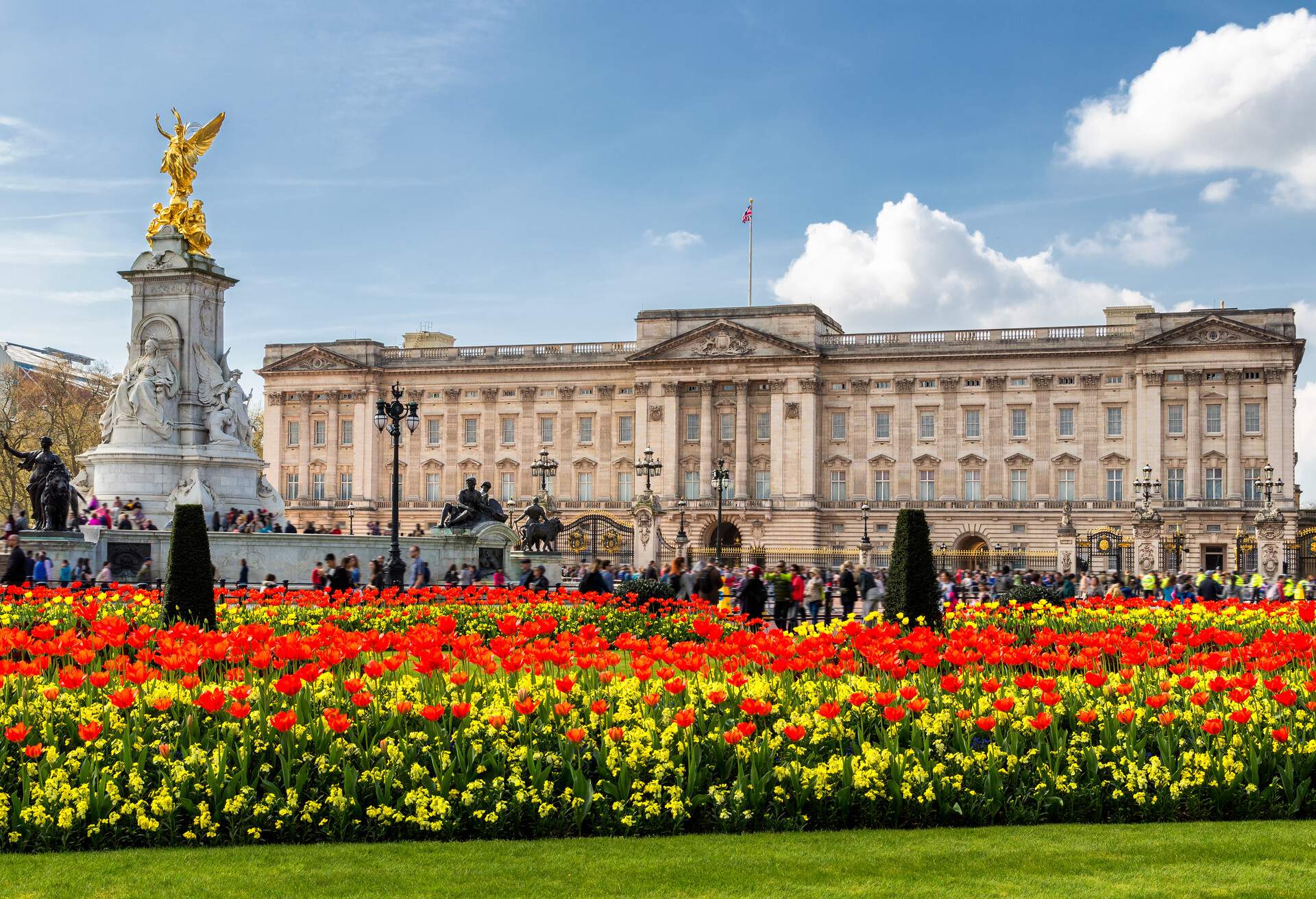 The crowd in front of Buckingham Palace and a lush garden with colourful blossoms.
