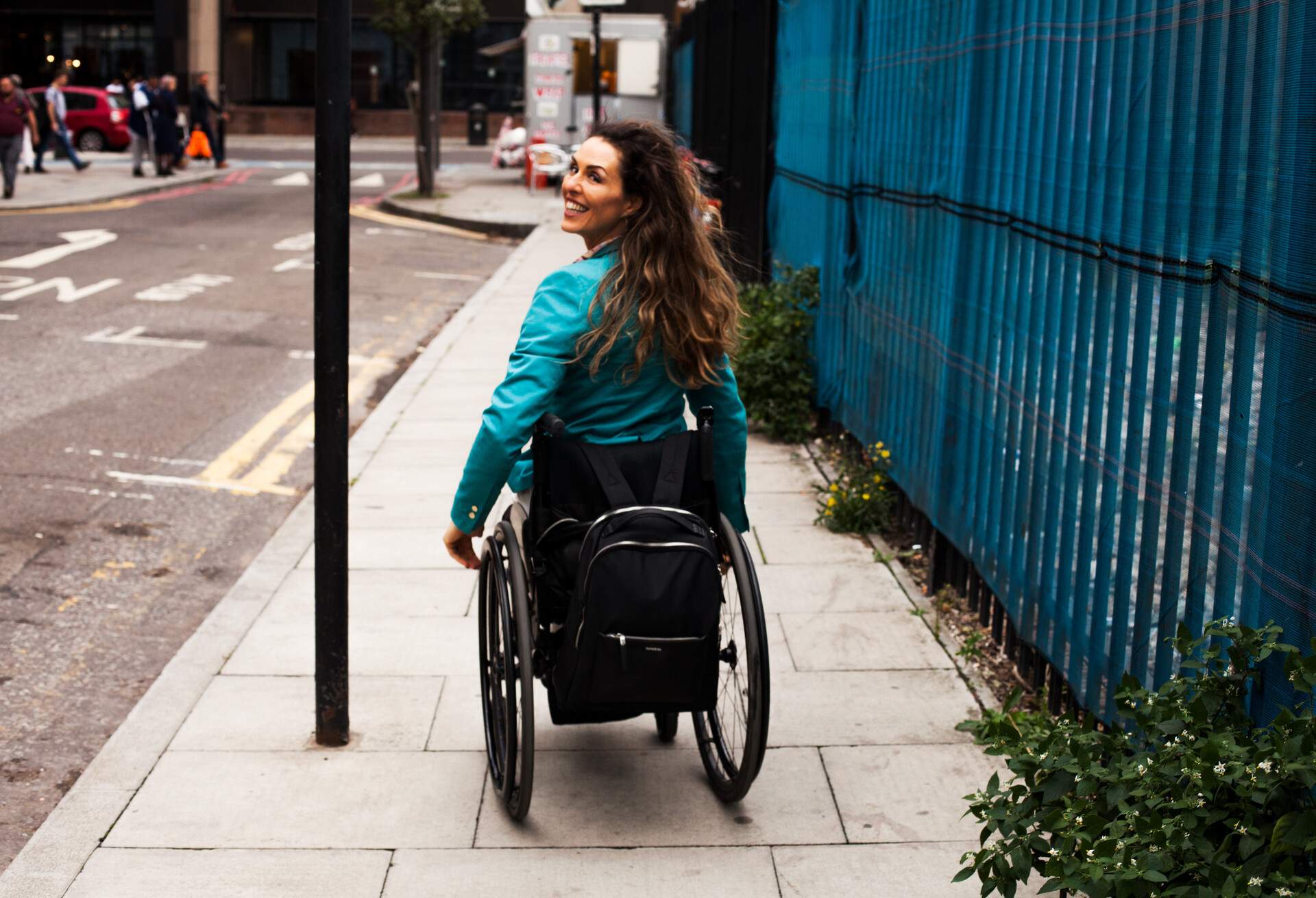 A happy woman in a wheelchair on the sidewalk.