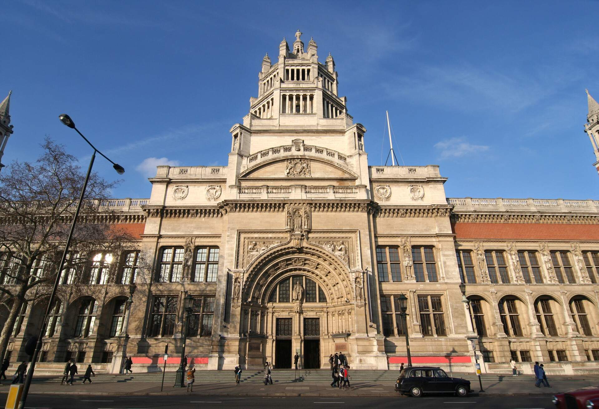 Victoria and Albert Museum is a museum with a façade of finely sculpted arch, twin doors, and a multilevel pillared tower on top.