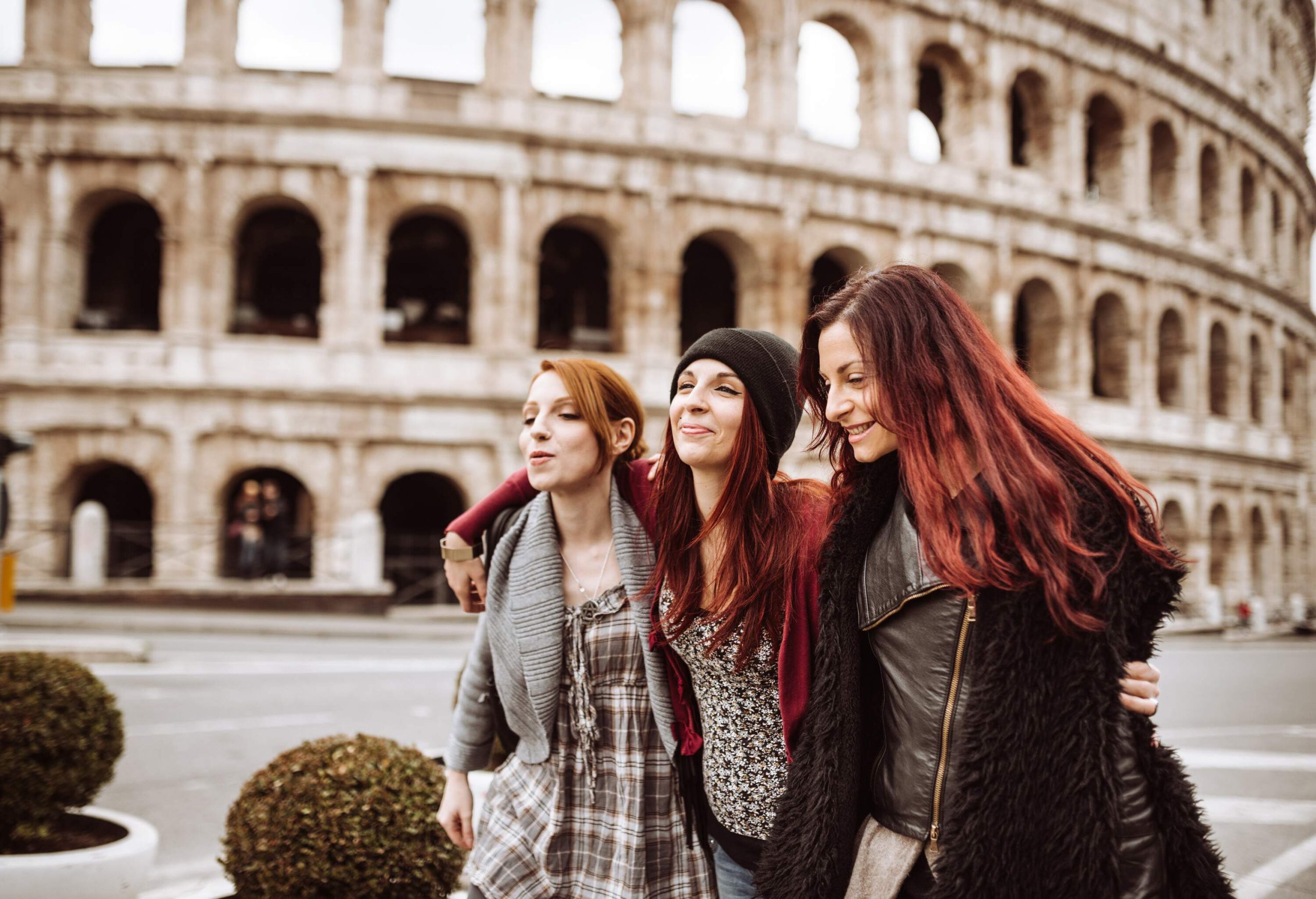 Tourists in winter clothing can be seen walking beside the iconic Roman Colosseum.