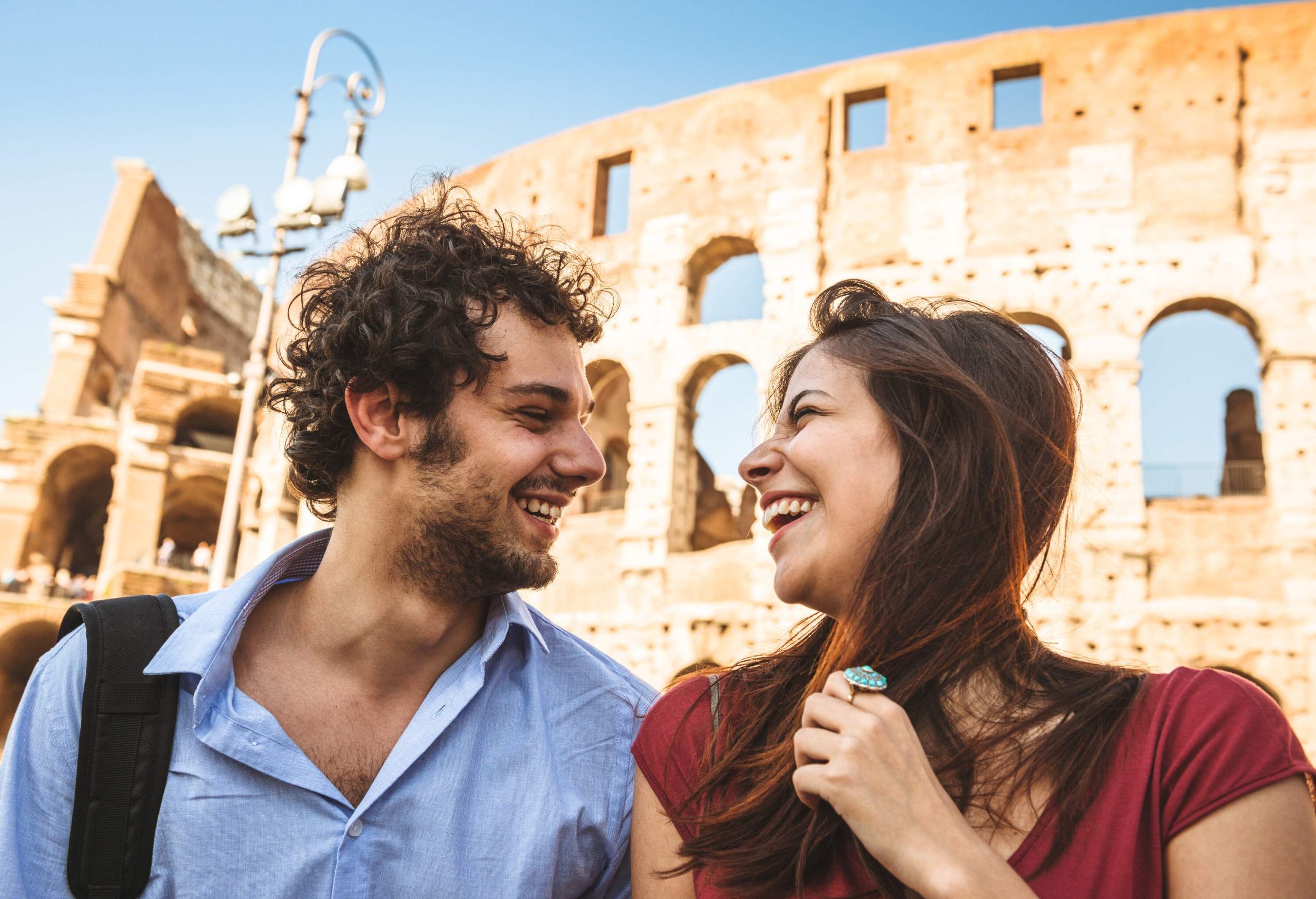 Happy couple smiling with colosseum in the background on a sunny spring day