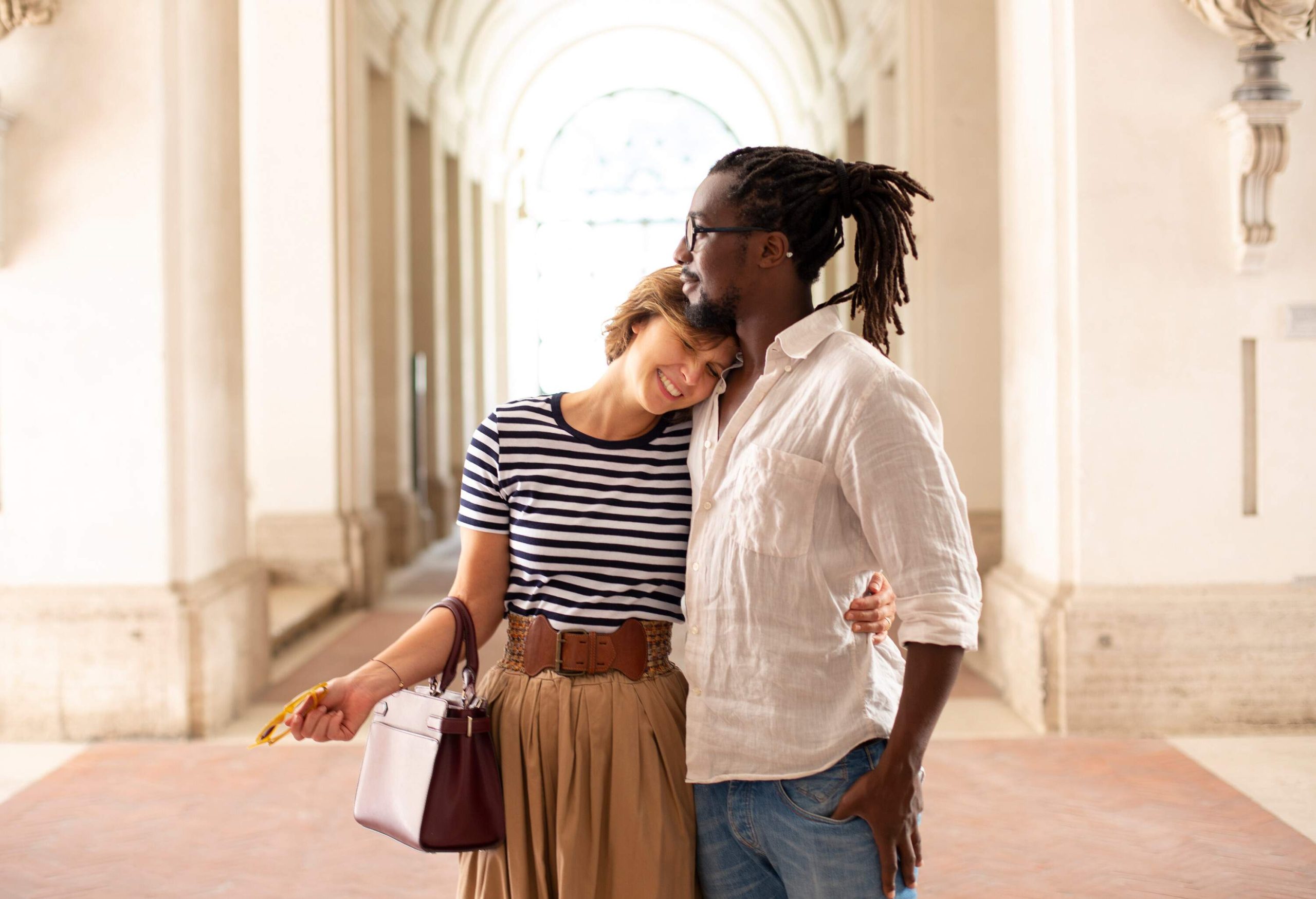 A woman in casual attire gives a man a hug and places her head on his chest.