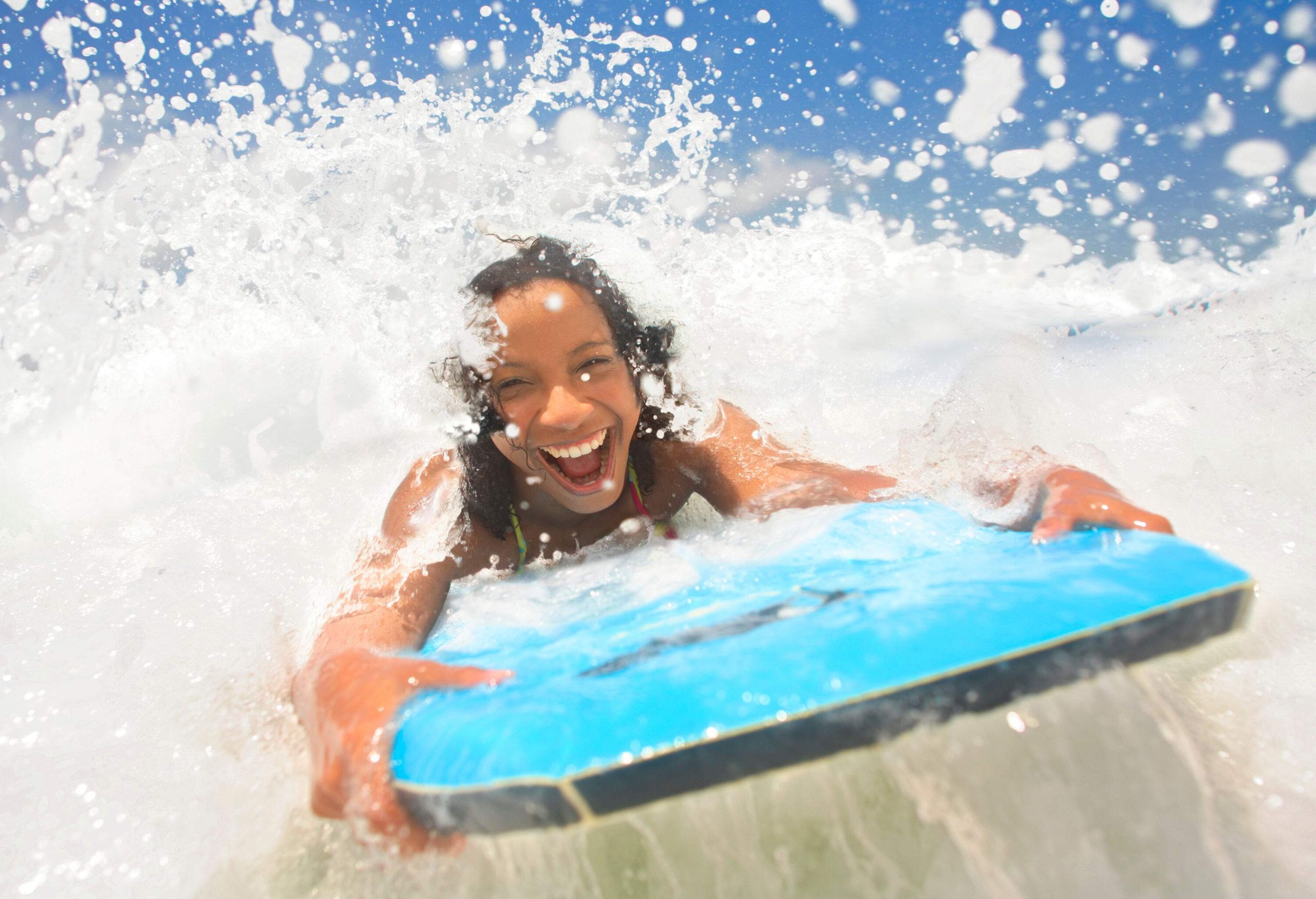 A happy female enjoys splashes of water while surfboarding.