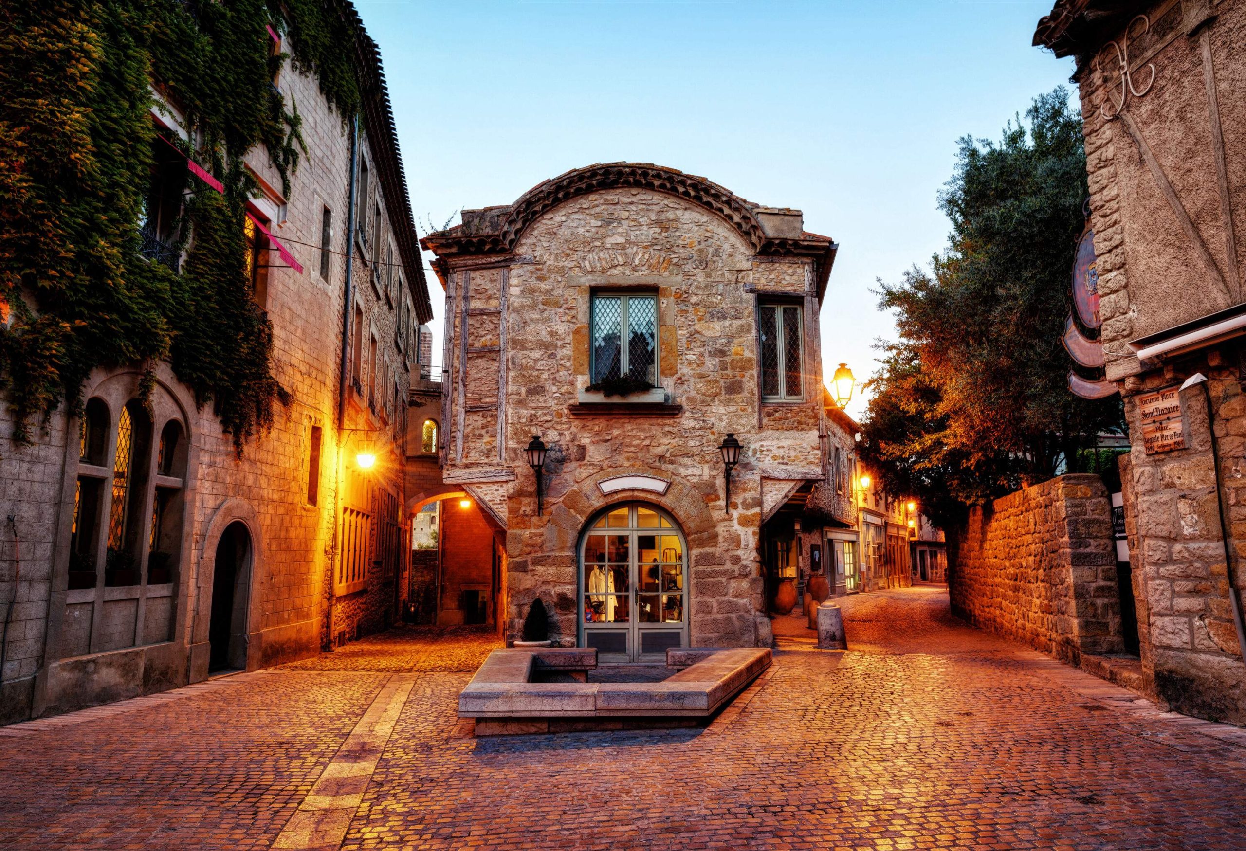 A cobbled alleyway runs behind the buildings at sunset.