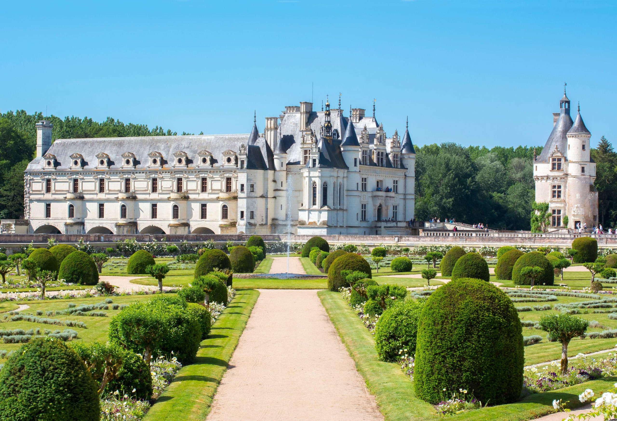 A lush garden in front of a Gothic-Renaissance chateau.