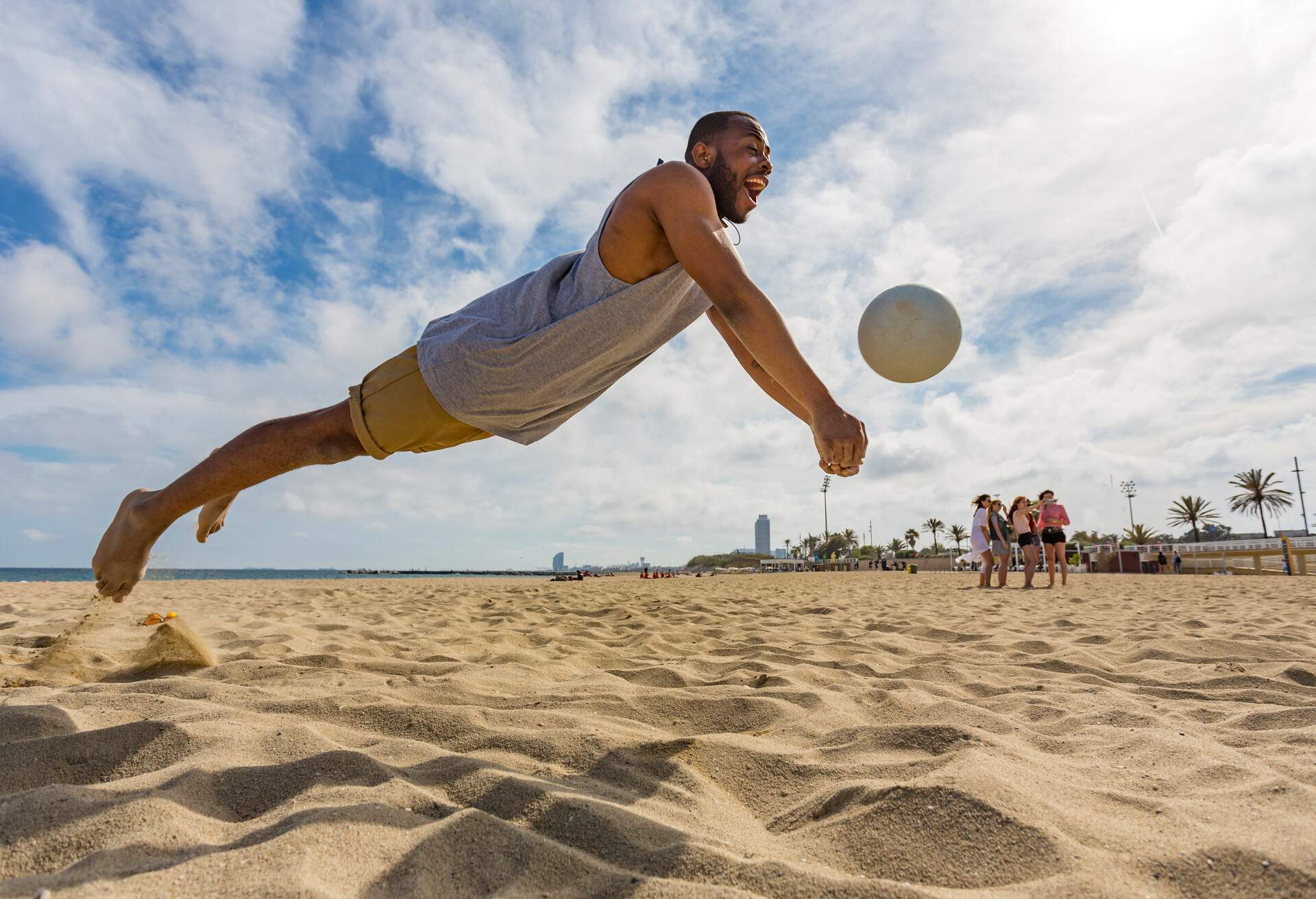 Active young man jumping to get the ball while playing beach volley ball in Barcelona, Spain