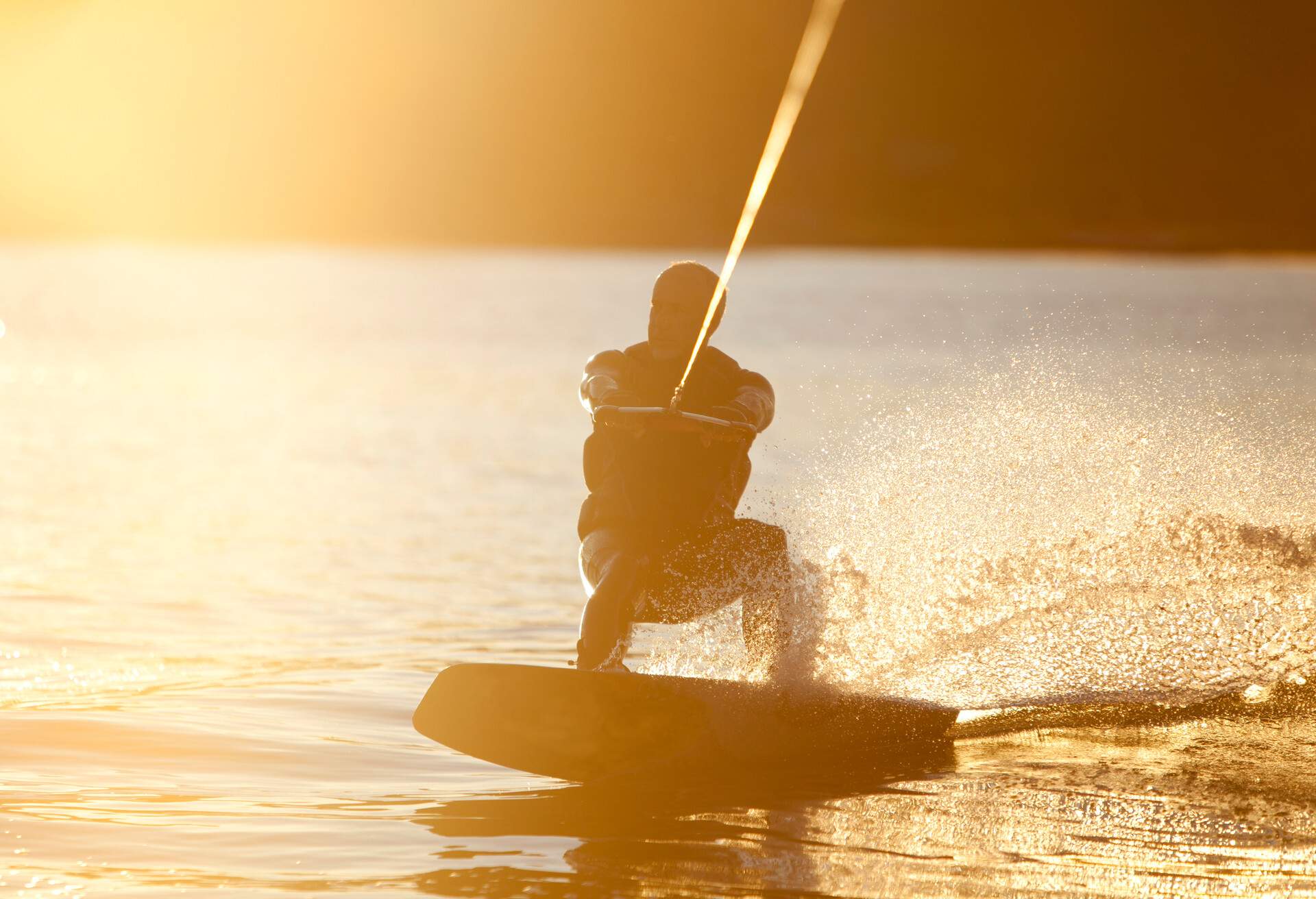 Wake boarder riding at sunset