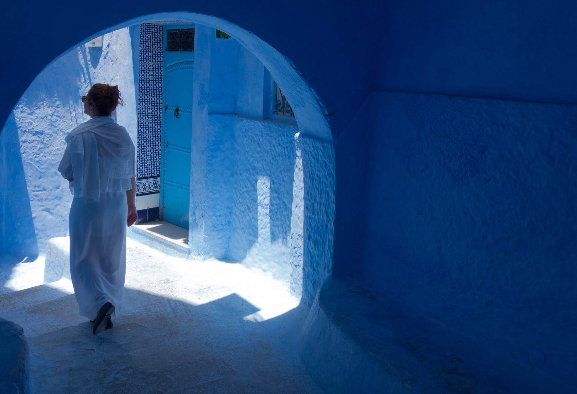Tourist woman with white djellaba walking the blue streets of Chefchaouen, Morocco.; Shutterstock ID 1176902047; Purpose: ; Brand (KAYAK, Momondo, Any):